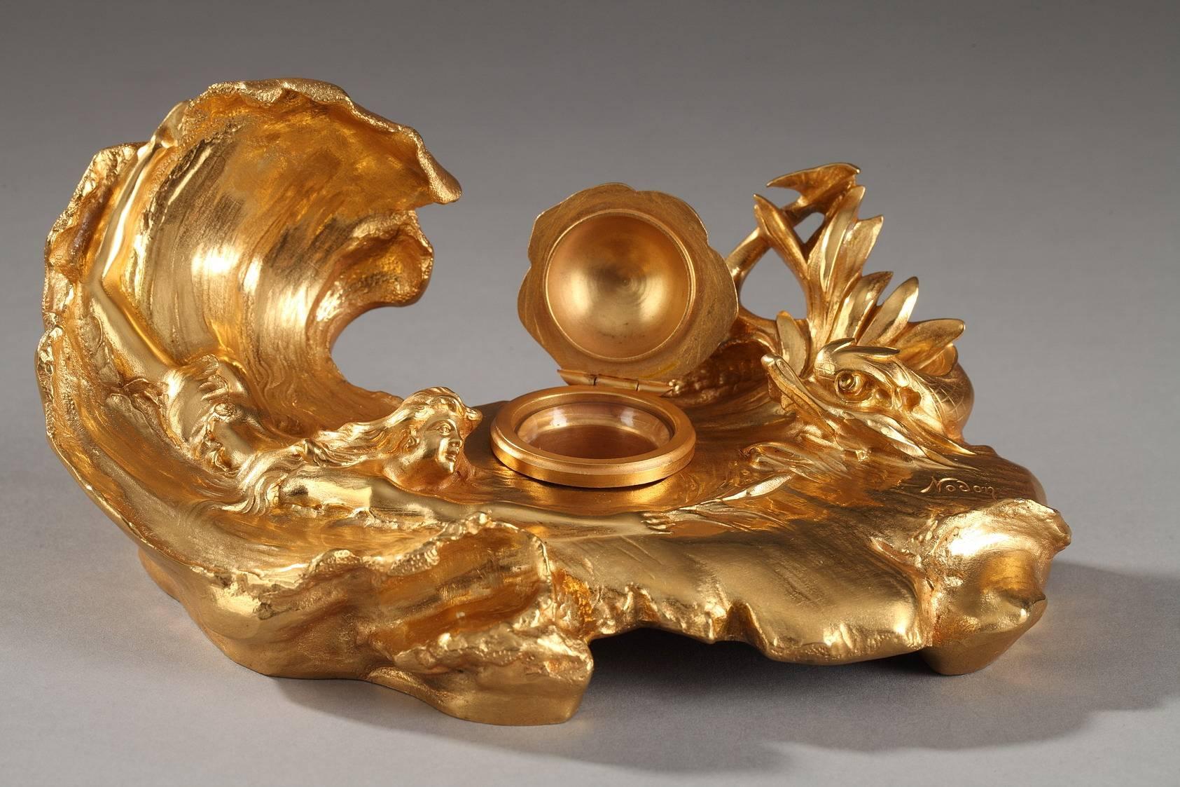 Small, gilt bronze inkwell, sculpted to portray a young woman swimming in the waves of the sea toward a dolphin. The predominance of curves and flowing lines, the inspiration from the natural world, as well as the feminine subject make this piece a