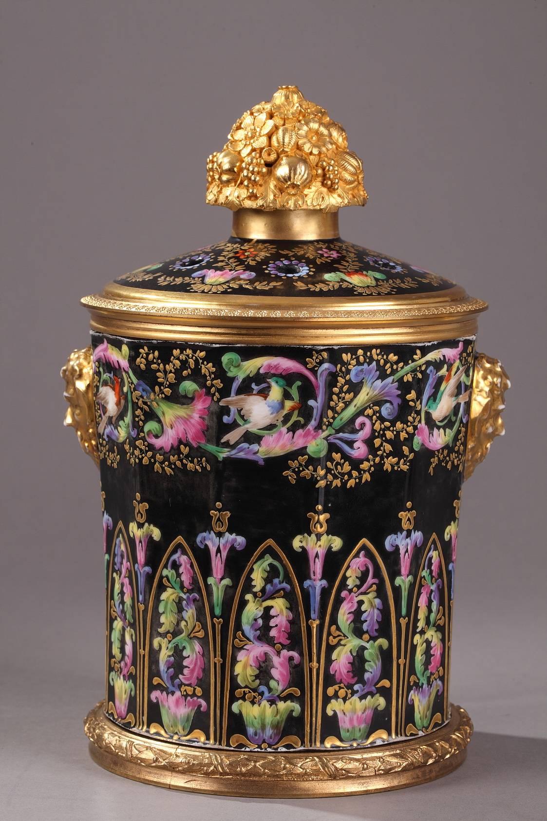Pair of pot-pourri vases covered with a pierced, multicolored, porcelain lid. They are richly decorated with flowering scrollwork and birds set over a black background highlighted with gold accents. The covers are painted with foliage and topped