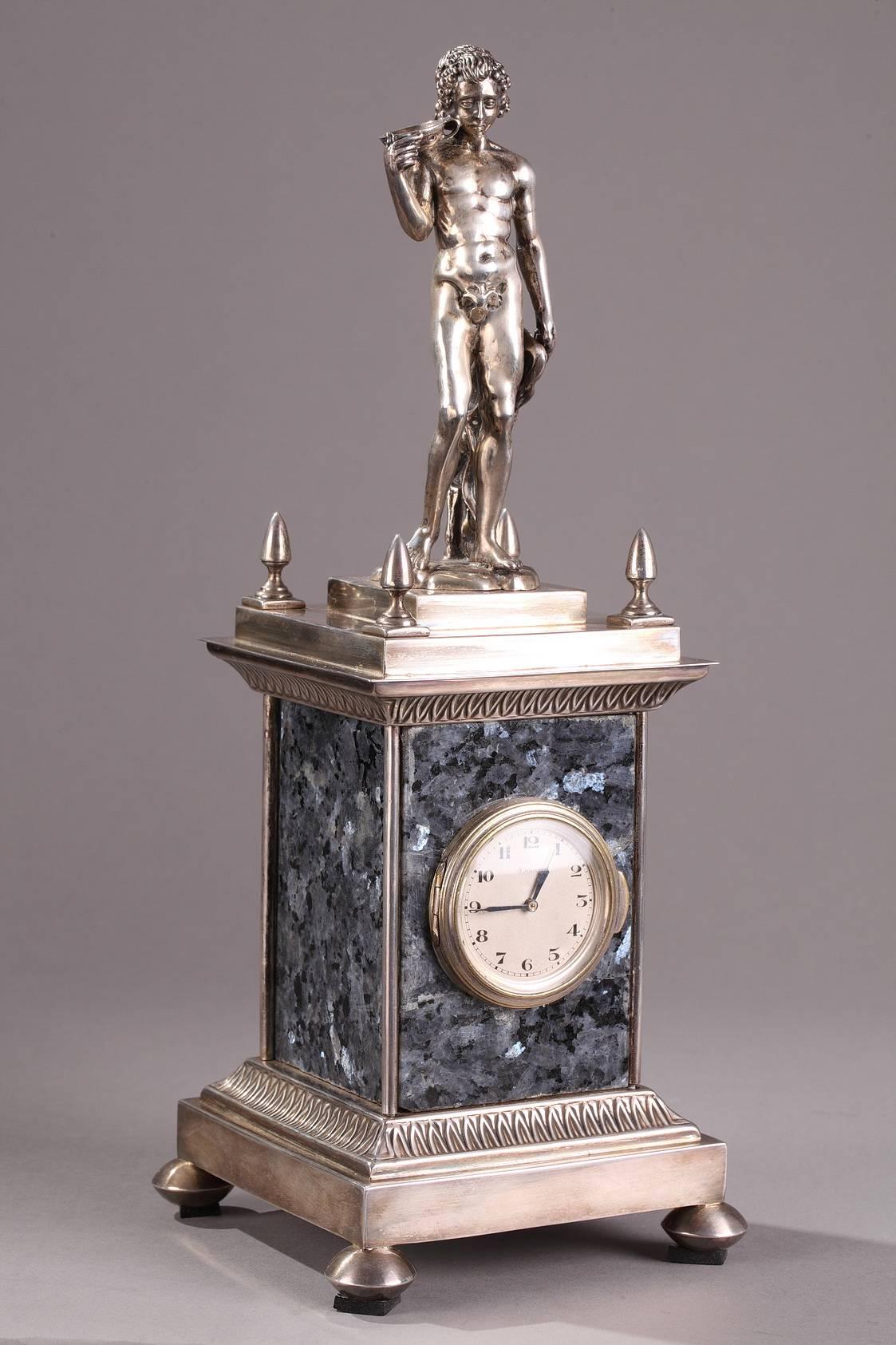 Silver and granite mantel clock topped with a young, nude Bacchus whose head is ringed with an ivy wreath. In Greco-Roman mythology Bacchus (Dionysus) is the god of wine, drunkenness, excess, and fertility. He holds a goblet of wine in one hand and