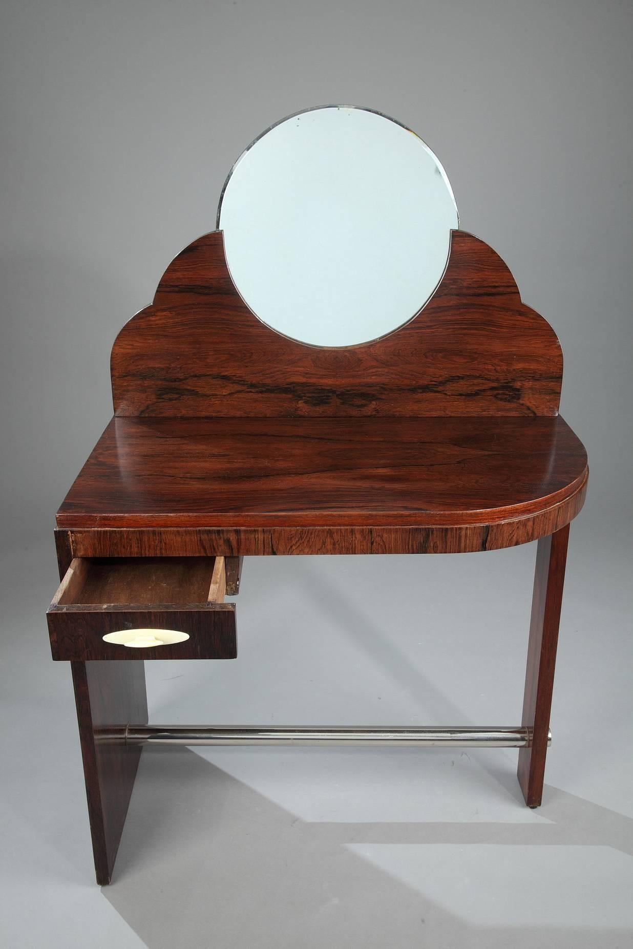 Elegant, rosewood Art Deco dressing table topped with a round mirror. An handle serves to open a small drawer in the front. The asymmetrical legs are connected with a round, metal brace. Marked: AD. Attributed to the Maison Dominique, André Domin &