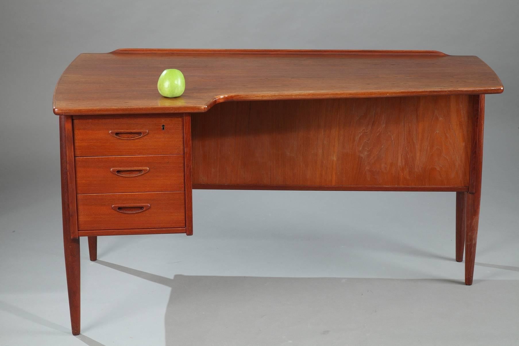 Scandinavian teak desk designed by Peter Løvig Nielsen in the 1950s. It is composed of three drawers on one side, a shelf and a container with a flap, on the other side. Danish work. Good vintage condition.

circa 1950.
Dimensions: L 137cm, P 80cm,