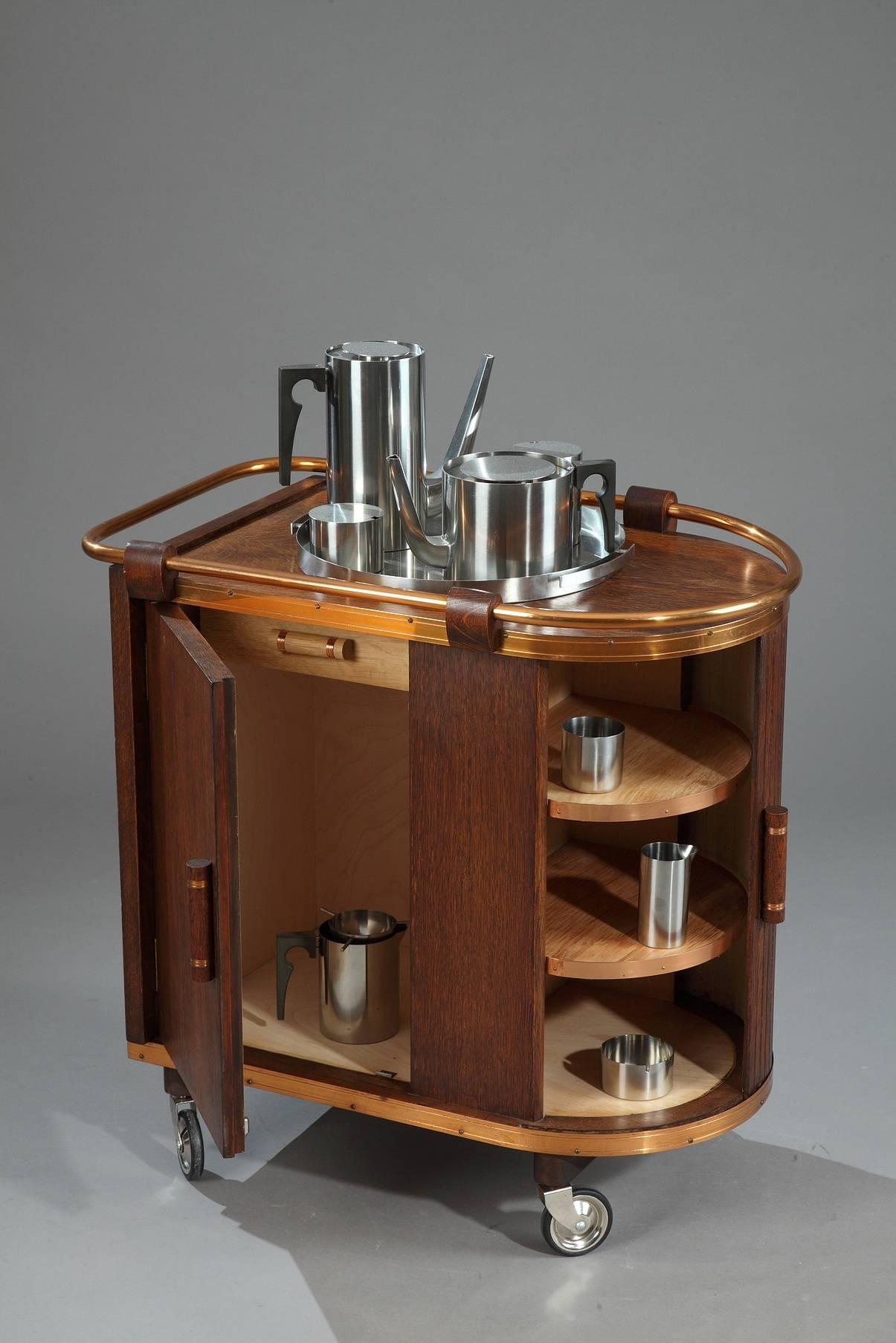 1960s oak bar cart. It is provided with a sliding door and two interior shelves and drawer. The doors and drawer are decorated with small cylindrical handles in copper. Very good vintage condition. 
We also have a bookcase with sliding