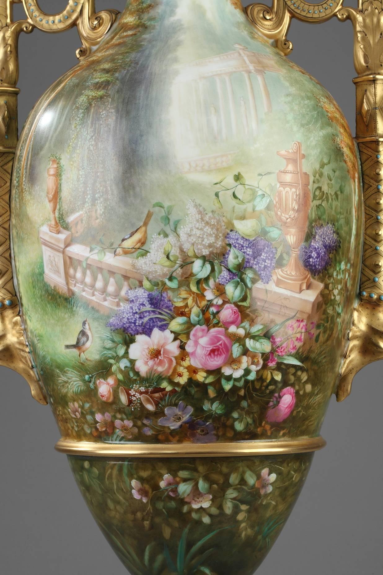 Large vase in hard Limoges porcelain with a multicolored landscape encircling the body of the neck, body and base. In one part of the scene, a pair of birds are looking at each other near a balustrade that is decorated with vases and partially