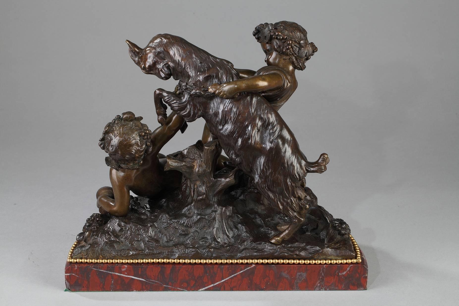 Bronzegruppe mit brauner Patina mit zwei Putten:: die mit einem Ziegenbock spielen:: auf felsigem Grund:: der mit Blumen und Trauben übersät ist. Die beiden Kinder tragen Weinrebenkränze:: und eines von ihnen hält einen leeren Becher. Die
