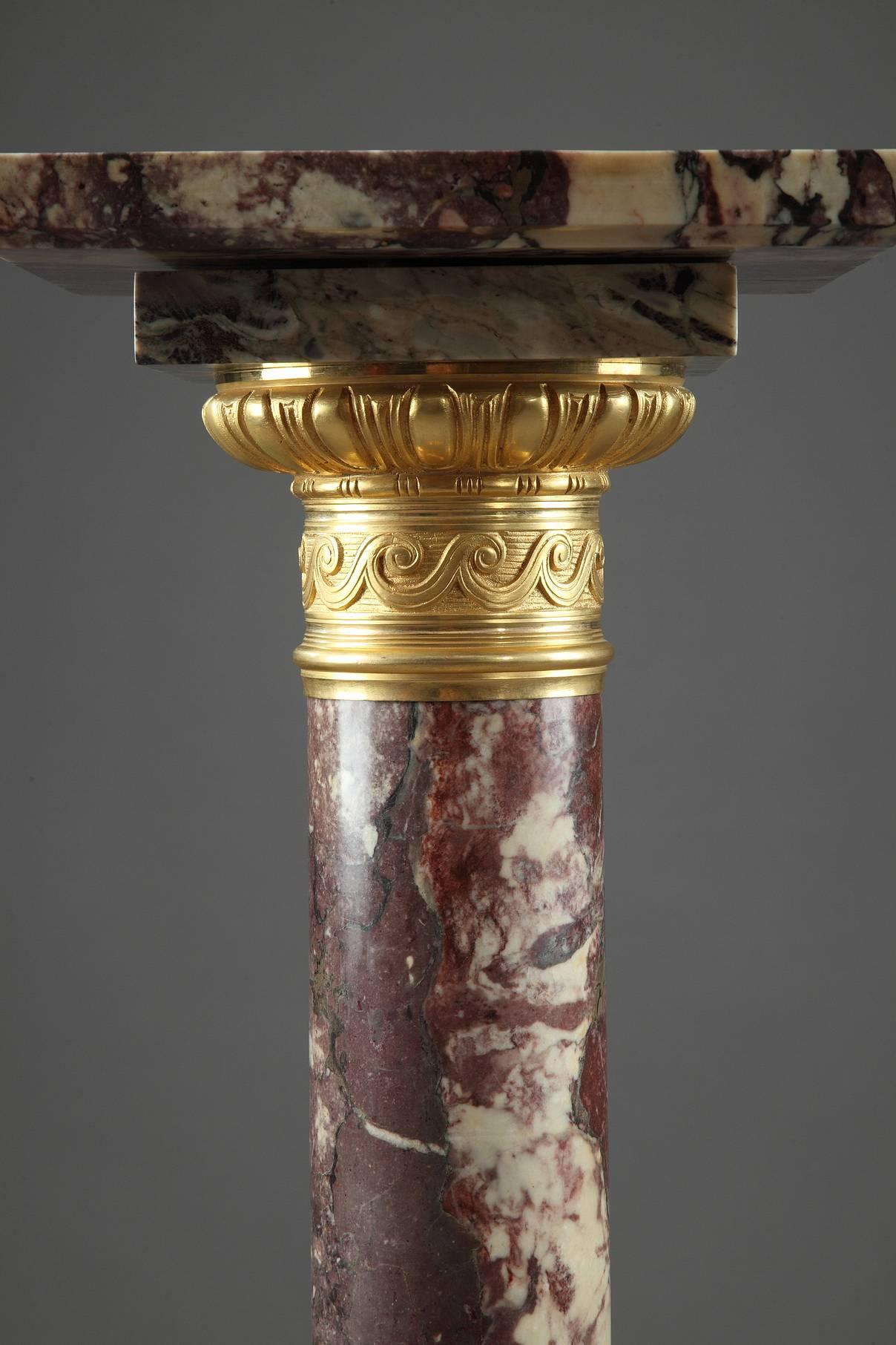 Display column in red, Griotte marble. The gilt and sculpted bronze capital is embellished with a frieze of stylized waves and ovals and the base is decorated with alternating ovals and palmettes. It is set on a square, terraced base. 19th