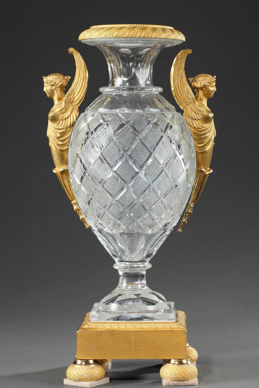 Pair of oval, crystal, Medici vases featuring gilt bronze sphinx-shaped handles. Each vase rests on a gilt bronze, square base that is sculpted with friezes of palmettes and rests on four half-ball feet that are decorated with spiralling beadwork.
