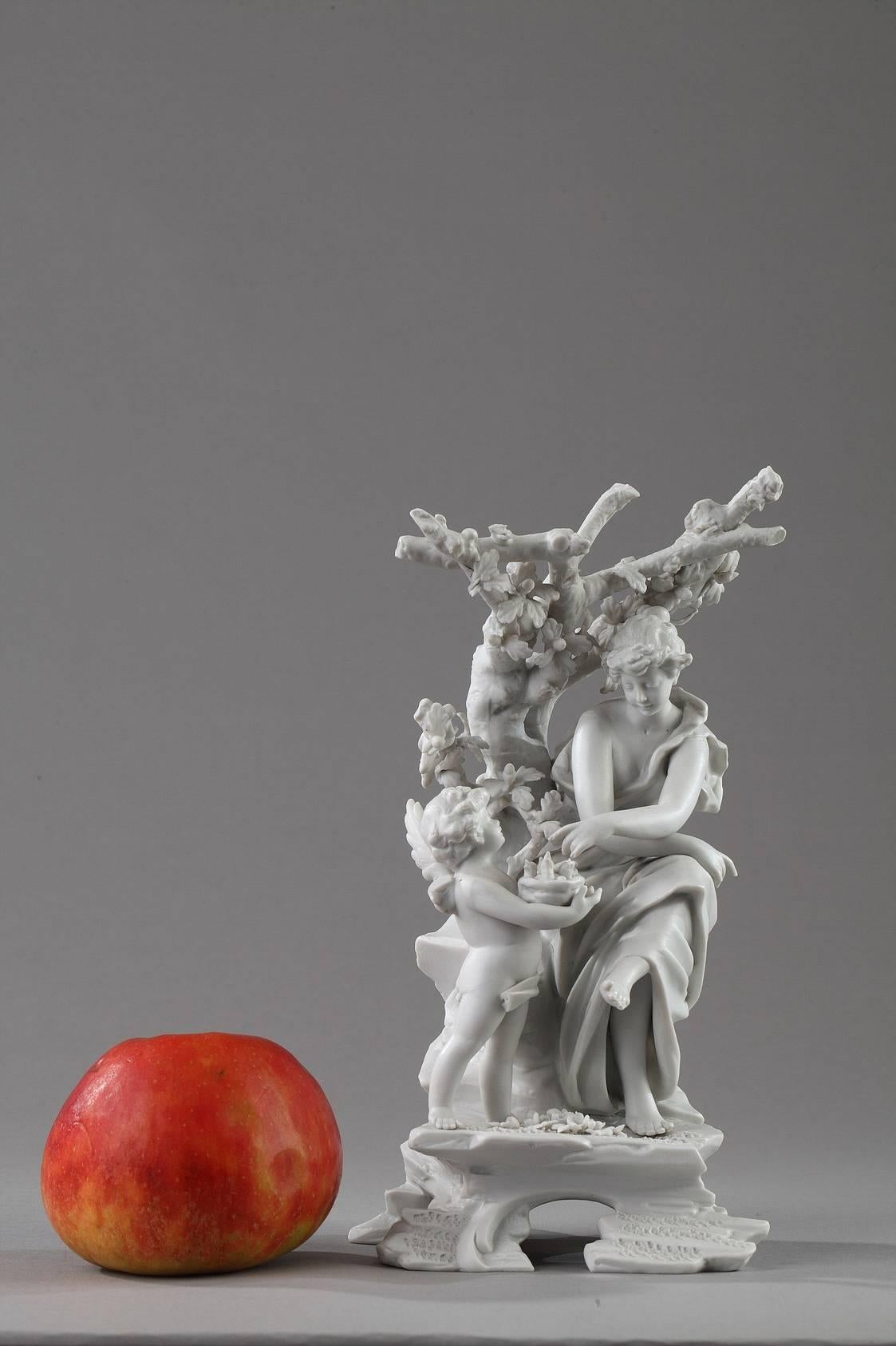 Small biscuit porcelain group featuring a cupid offering a young woman a nest filled with newly hatched chicks. She is seated on a rock in the shade of a tree. The symbolism used in the piece all evokes the Spring. Blue mark on the base from