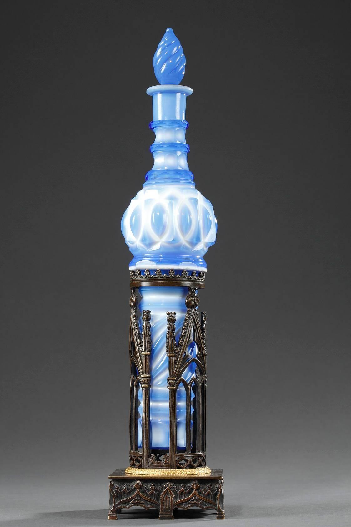Crystal decanter with blue and white overlay used for serving Carmelite Water, a floral-based liqueur. The decanter, with its spiraling, pointed stopper is embellished with twisting and intertwining patterns. It nestles into a patinated, Neo-Gothic