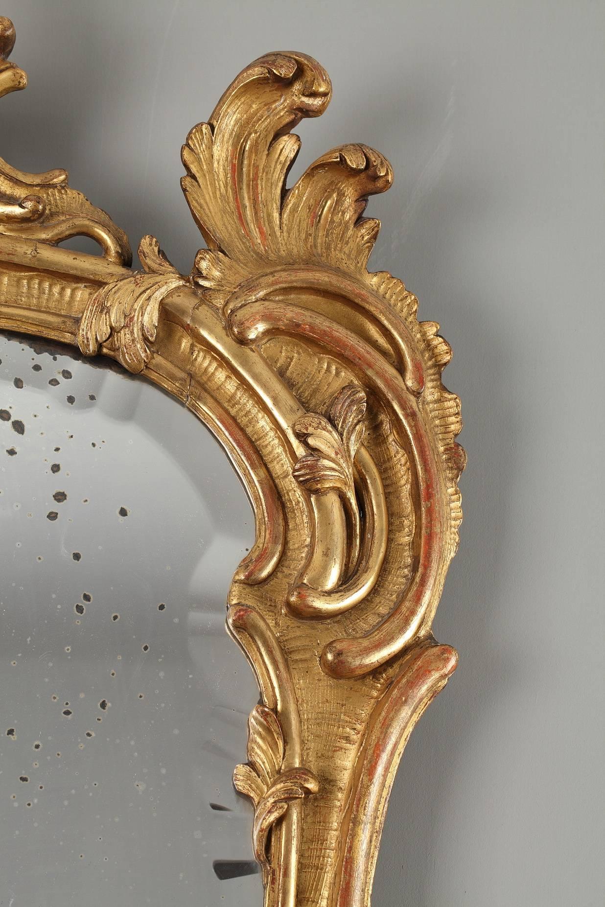 Mid-18th century mirror in gilt and sculpted wood, embellished with distressed leaves, foliated scrolls, and branches. This decorative opulence is typical for the objects under Louis XV. Good vintage condition, with slight traces of use.

circa