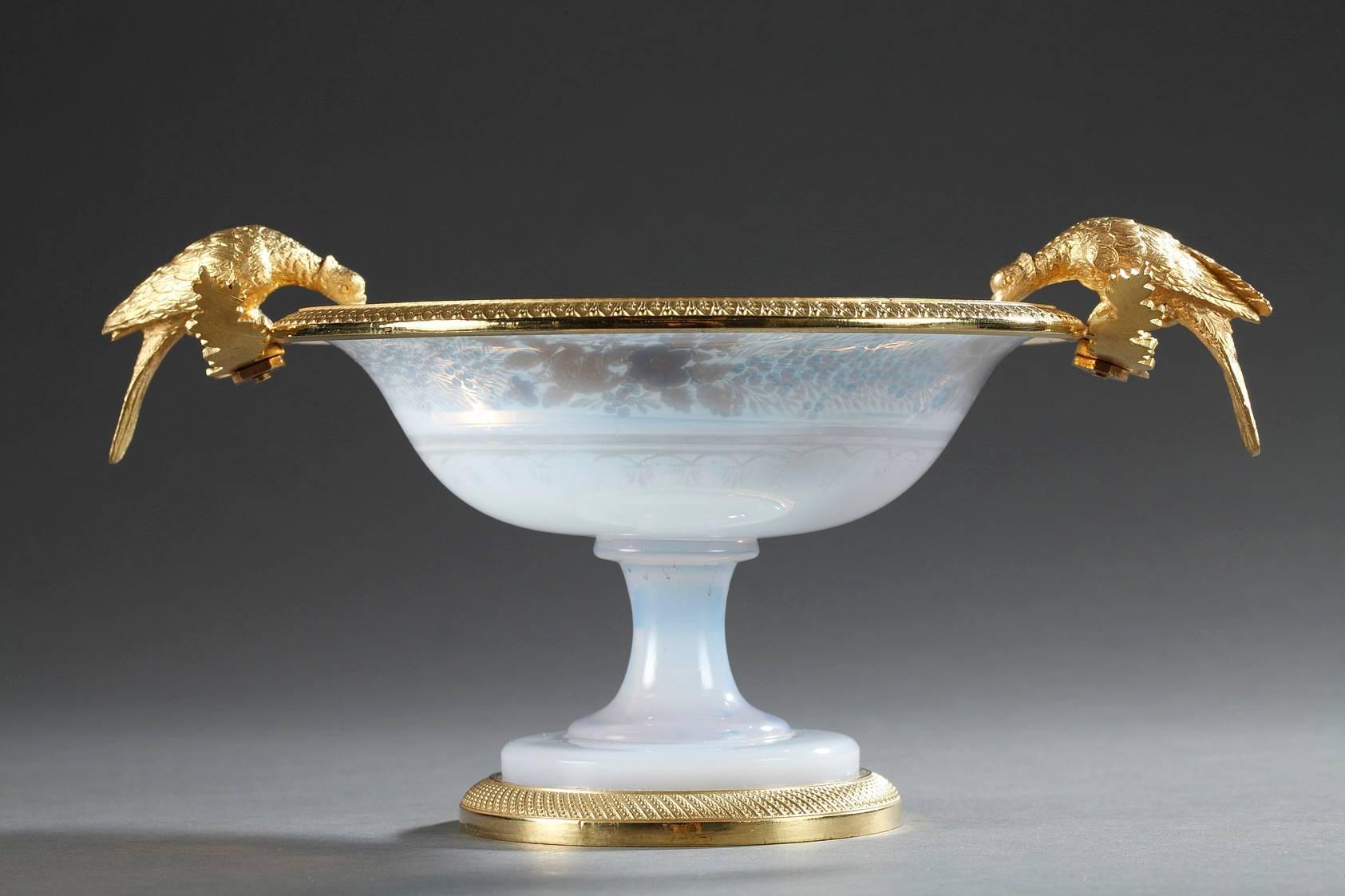 White opaline cup with gilt bronze mounts. The upper, gilded rim is finely sculpted with water-leaf, and the foot is encircled with a gilded ring decorated with angled grooves with beads. The handles are in the form of two pheasants that are resting
