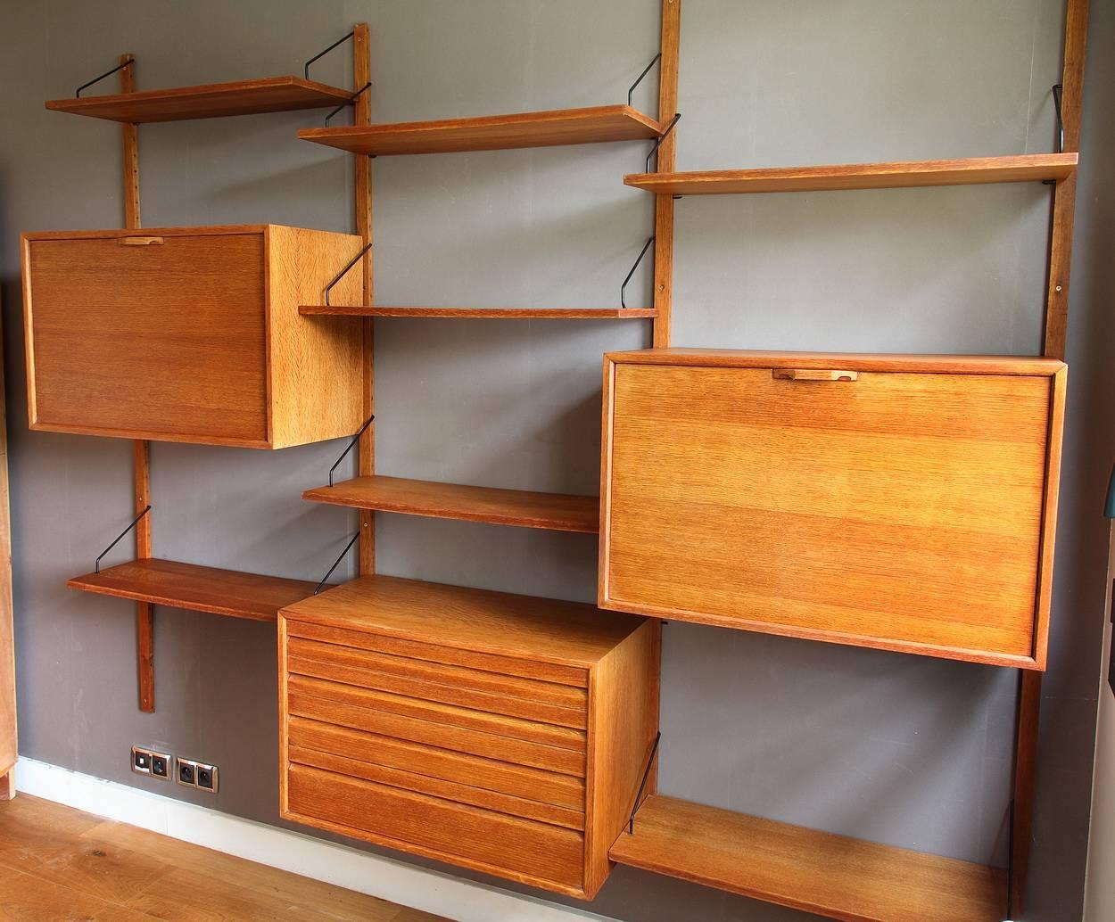 Poul Cadovius oak wall unit system from the 1960s. It is composed of four vertical ladders with seven shelves and three containers : Two with flap doors and one with drawers. Danish modern Royal System design.

The set is composed of :
One