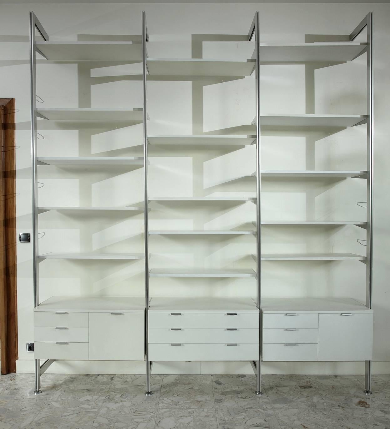 CSS white lacquered wood and stainless steel modular wall unit designed by George Nelson for Herman Miller in 1957 and edited between 1959 and 1973. It is composed of 3 vertical ladders, 15 shelves and 3 storage compartments with sliding drawers.