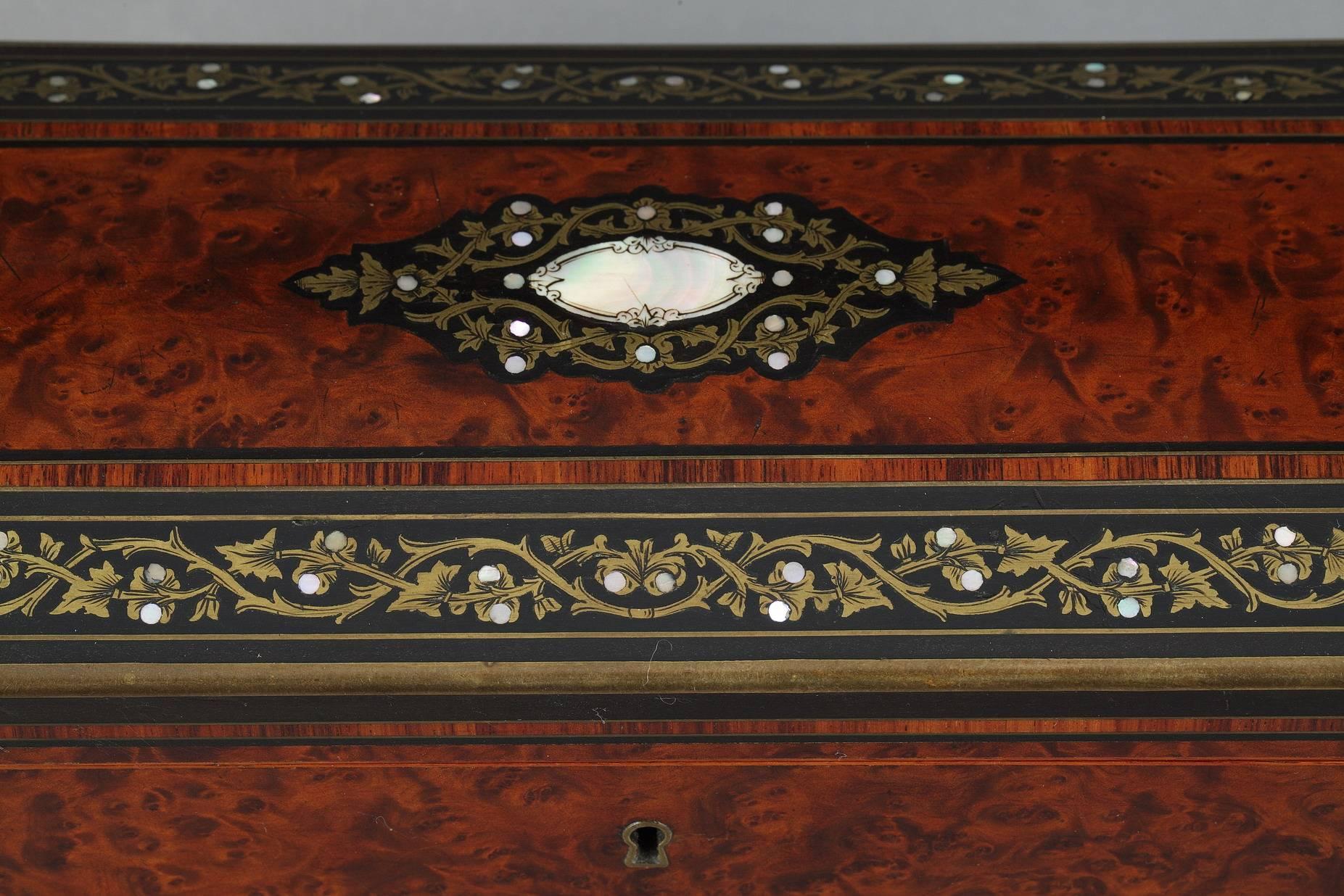 Octagonal-shaped?casket?in wood, the drop-leaf lid is decorated with brass and mother-of-pearl inlay featuring a central medallion and foliated interlace. The interior is composed of a compartment lined with blue fabric that has some traces of use.