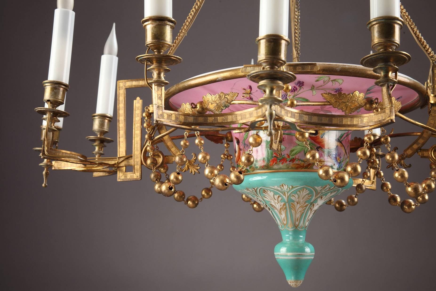 Interesting twelve-light chandelier decorated with multicolored birds, flowers, foliage and butterflies on pink and green background. Candle arms distributed by groups of three extend from the central piece and are hanged on the crown atop by