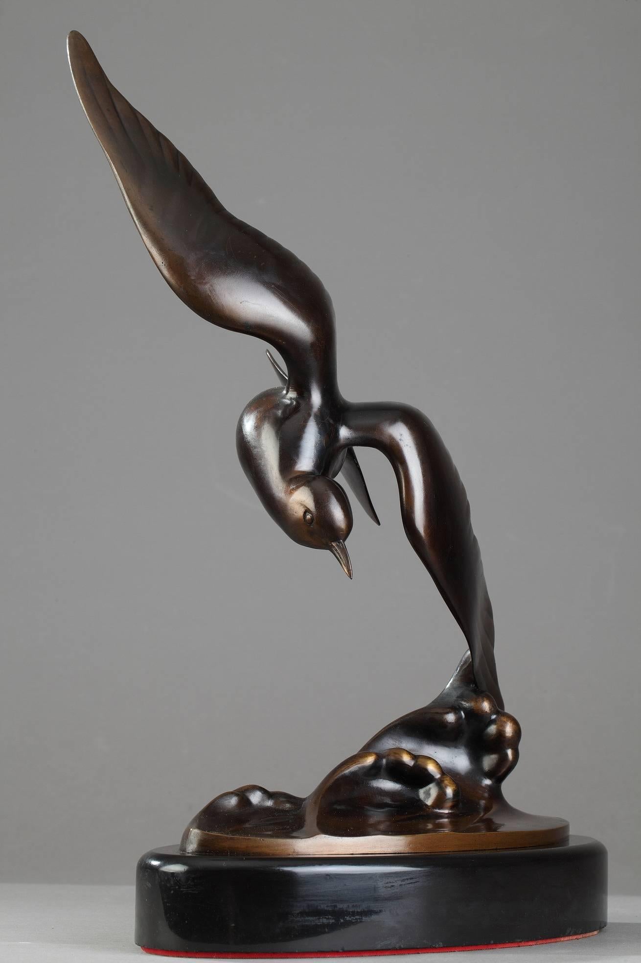 Early 20th century patinated bronze sculpture of a flying gull skimming the crest of a wave, mounted on an oval black marble base. Signed on the wave : 