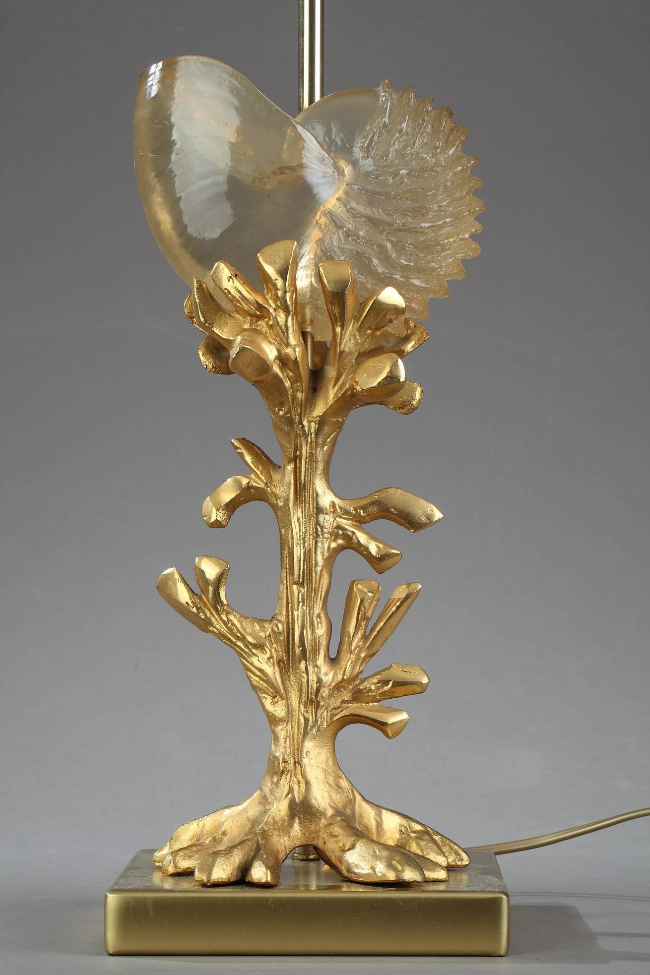 A gilded bronze and brass table lamp in Charles House style. It is decorated with a branch of coral and a translucent resin nautilus. Charles House create during the 1970s a collection of sculptural lamps inspired by nature. Among the various