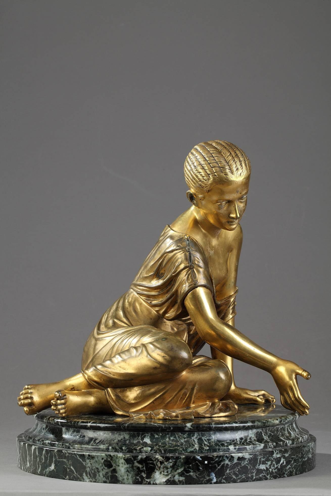 Late 19th century gilt bronze figurine featuring a young girl playing knucklebones. She wears a chiton, which has slipped to expose her right shoulder. Round green 