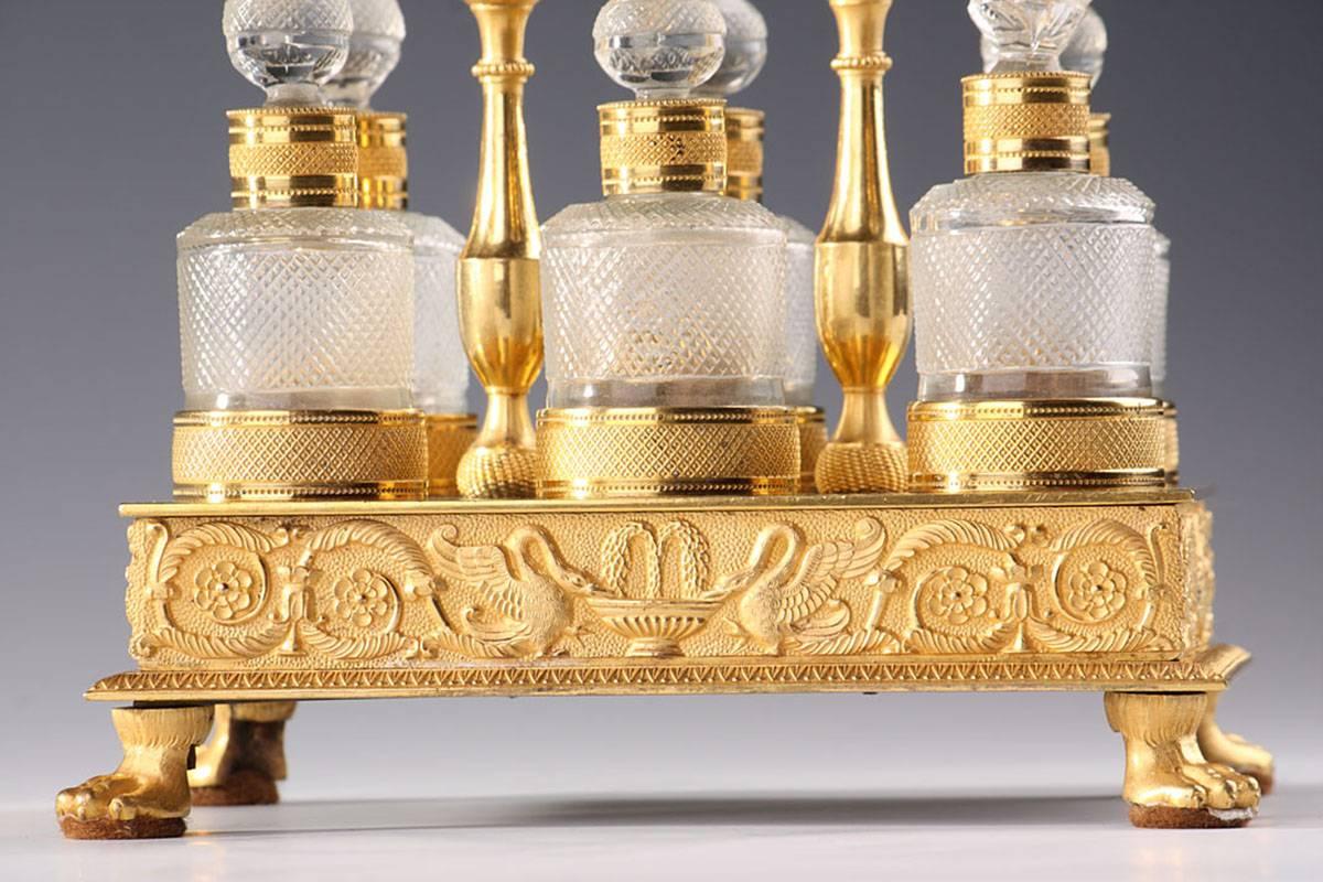 Fine handmade cut-crystal and ormolu cellaret with six perfume flasks and their stoppers embellished with geometric and rosette patterns. The gilt bronze rectangular tray is decorated with an admirably crafted frieze. The frieze is intricately