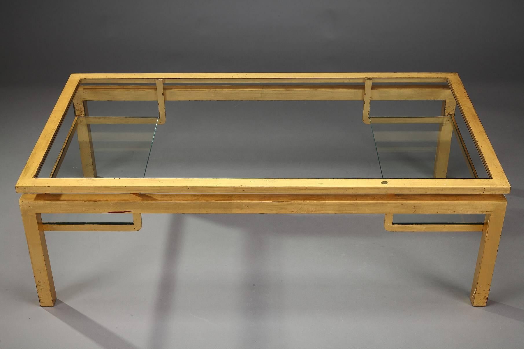 Rectangular coffee table in gilded metal with glass top, designed by Guy Lefèvre for Maison Jansen (Paris, 1880-1989). It is provided with two glass display shelves underneath. Very beautiful patina, a great Classic of the 1970s. Good vintage