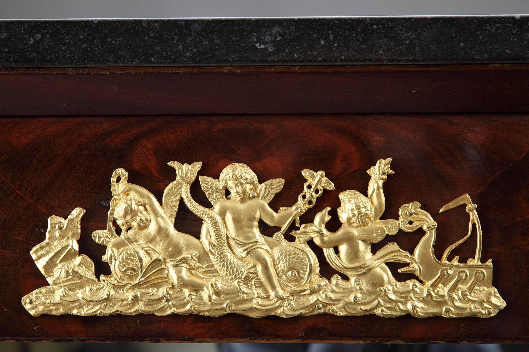 Early 19th century console in mahogany and mahogany veneer. Exquisite gilt bronze decoration composed of putti and exotic characters and animals. The exoticism fashion which appeared early in the 18th century with everything coming from the Middle