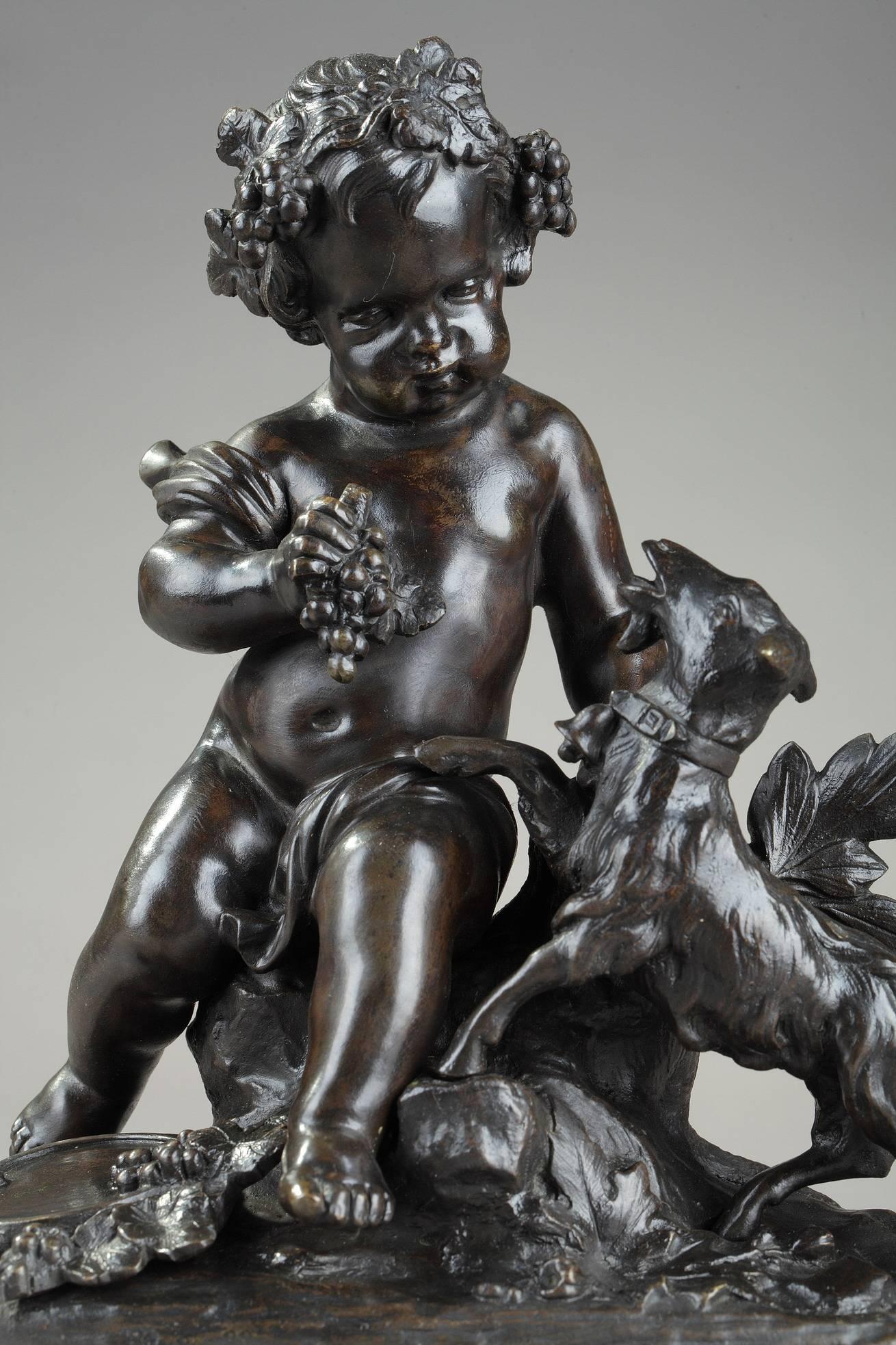 Small bronze group with brown patina featuring Bacchus child, playing with a billy goat. He is crowned with vine branches and holds a bunch of grapes. A tambourine and several grapes are spread at his feet. The crown of vine branches, the billy goat