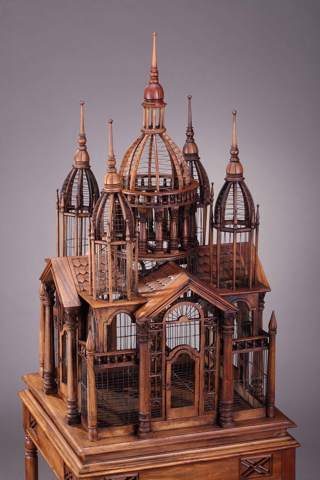 Large 20th century Victorian style mahogany cathedral bird cage. It is composed of two parts, the upper cage with a large center dome and four rounded turrets, several portels and columns. It is set on an openwork base above four elegant legs with