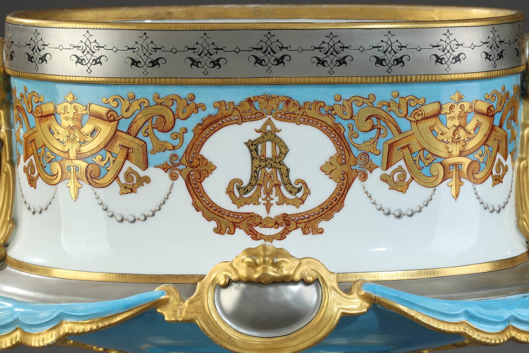 Large 19th century porcelain jardinière. It is decorated with gilded masks, foliated interlace and monogram AR on white medallions framed in a gold-colored border, on a white and blue background. The collar and foot are adorned with arabesques. The