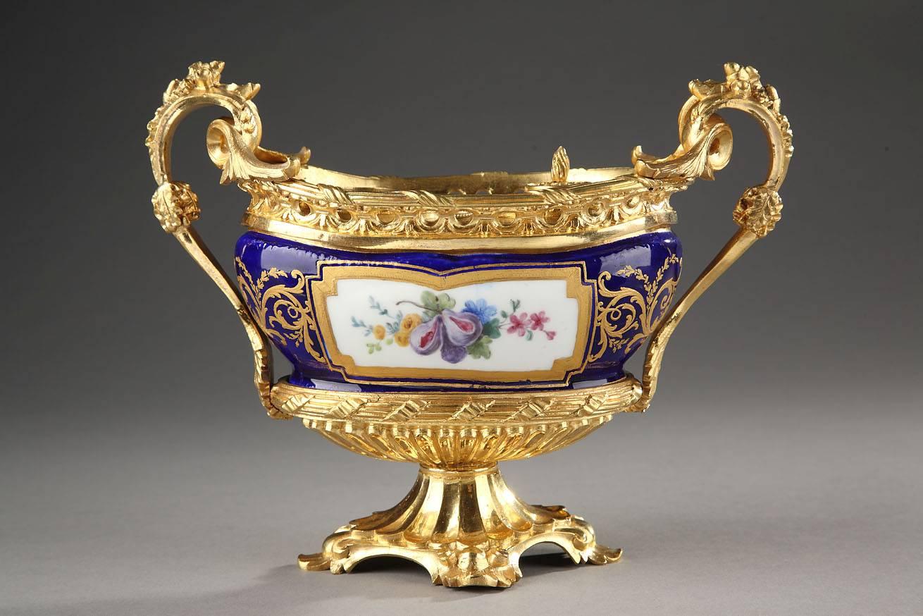French Napoleon III oval-shaped inkwell. The inkstand is crafted in 18th century Sevres soft-paste porcelain, decorated with multicolored flowers in a white medallion ornate with golden foliage on a blue background regilded in the 19th century.
