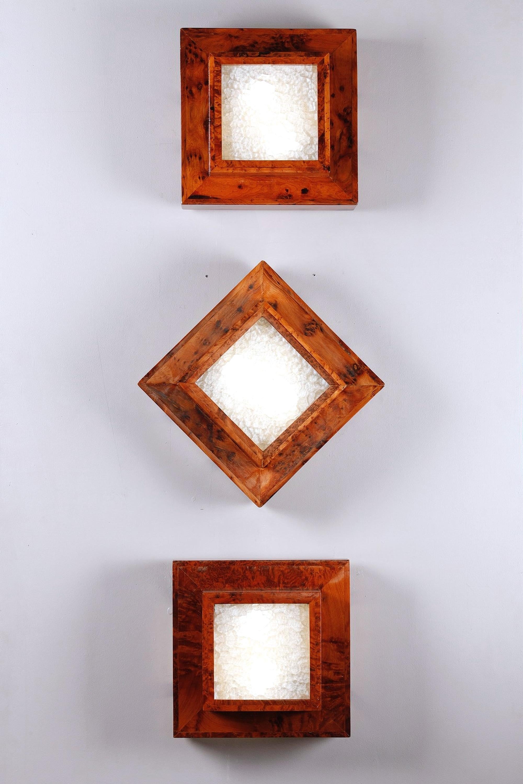 Elegant set of three large Art Deco ceiling lights, which can also be used as wall lights. Each piece features a geometrically assertive frame in elm burr veneer, magnifying the lively look of the wood, and a central diffuser in hammered glass,