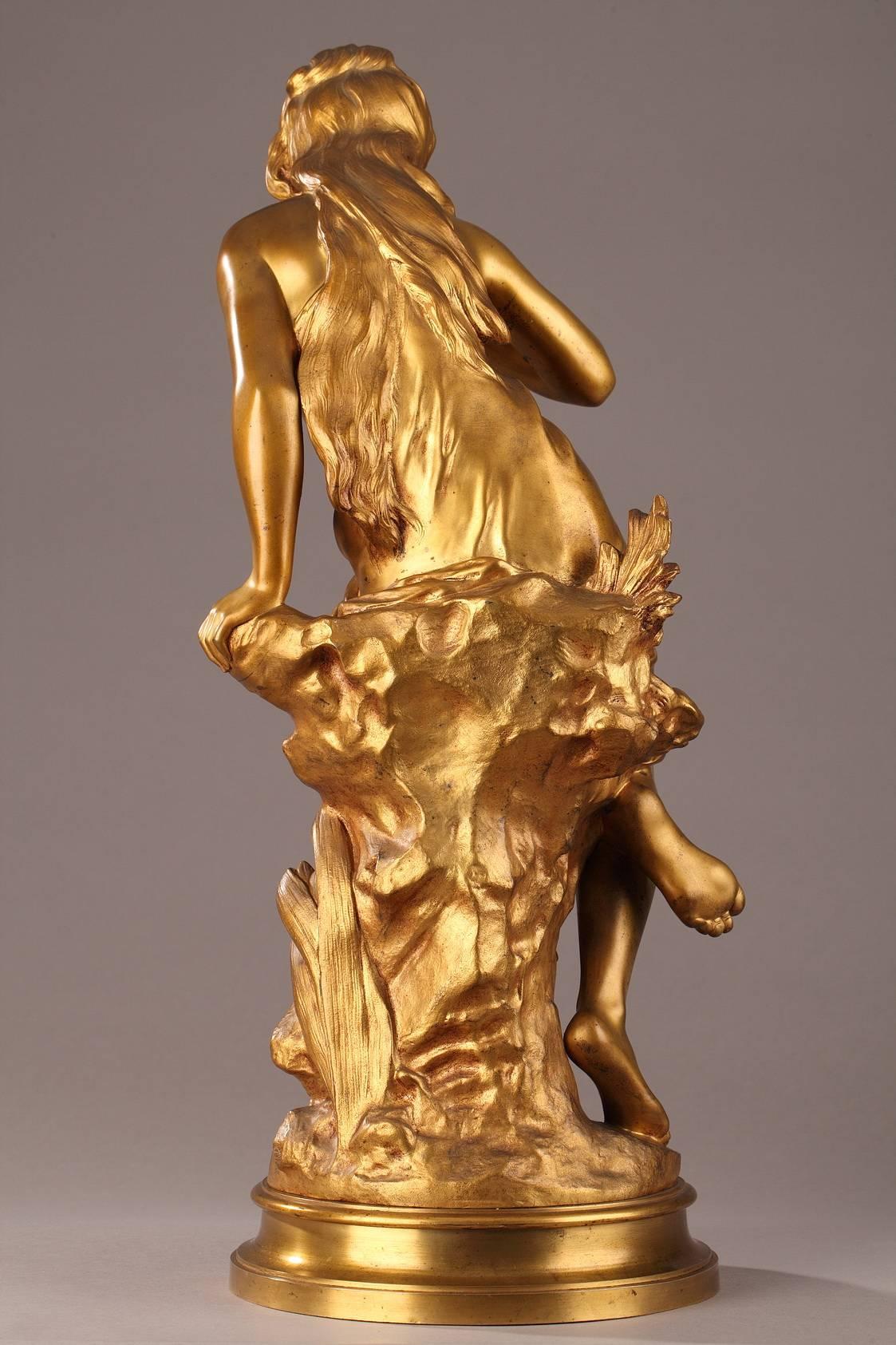 Gilt bronze sculpture titled “La Source” (The Spring), portraying a young woman drinking water from a spring using a shell as her cup. The sculpture is set on a terraced, circular base. Signed: 