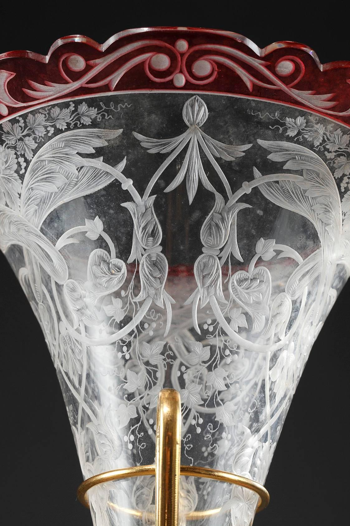 Red and transparent crystal centerpiece composed of a flared vase and cup. They are engraved with leafy rinceau, grape vines, and scrolling foliage. Gilt bronze mounts are decorated with antique cameos.