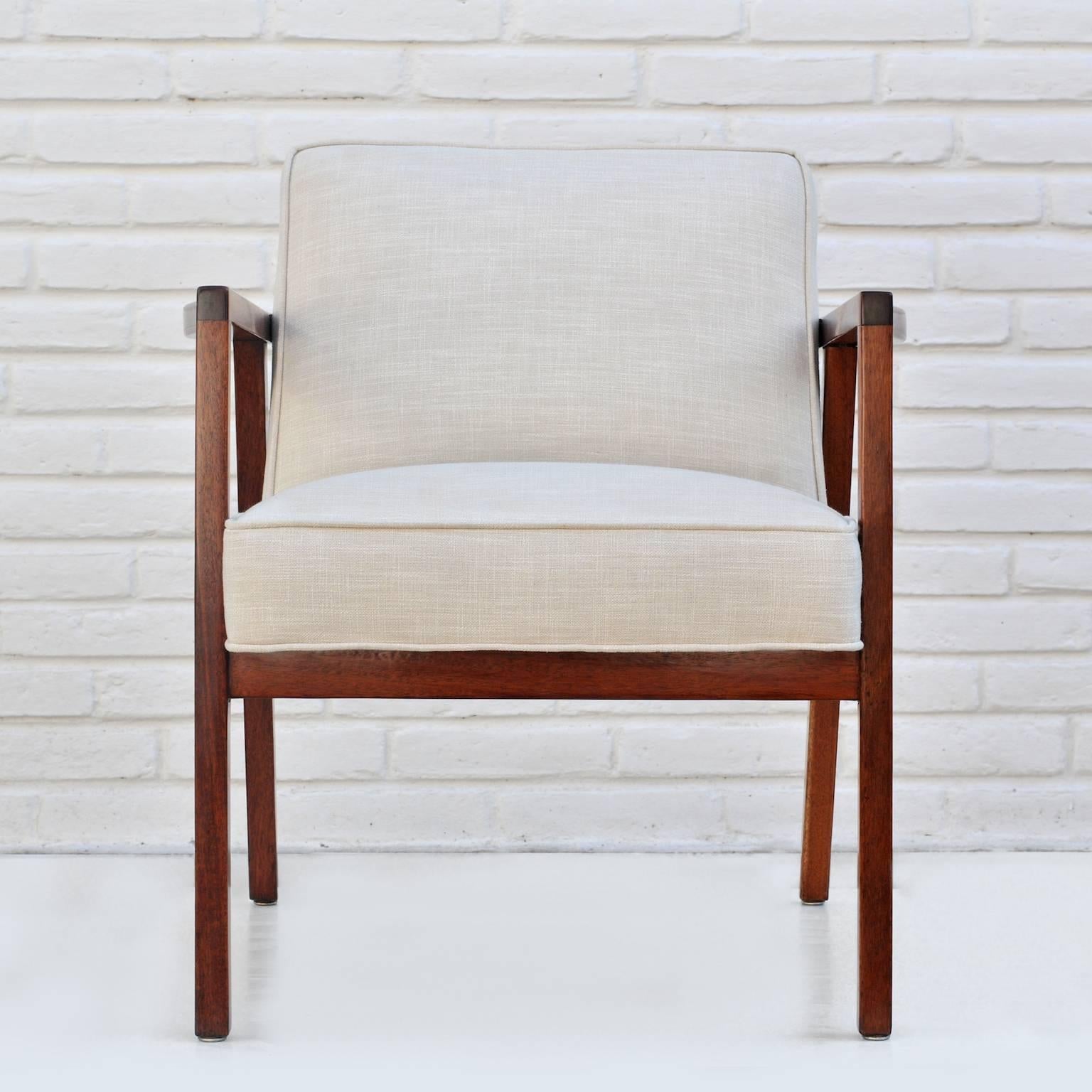 An elegant armchair made in Mexico with a crisp Silhouette. This particular mahogany has beautiful deep red tones that are brought out by its creme upholstery.