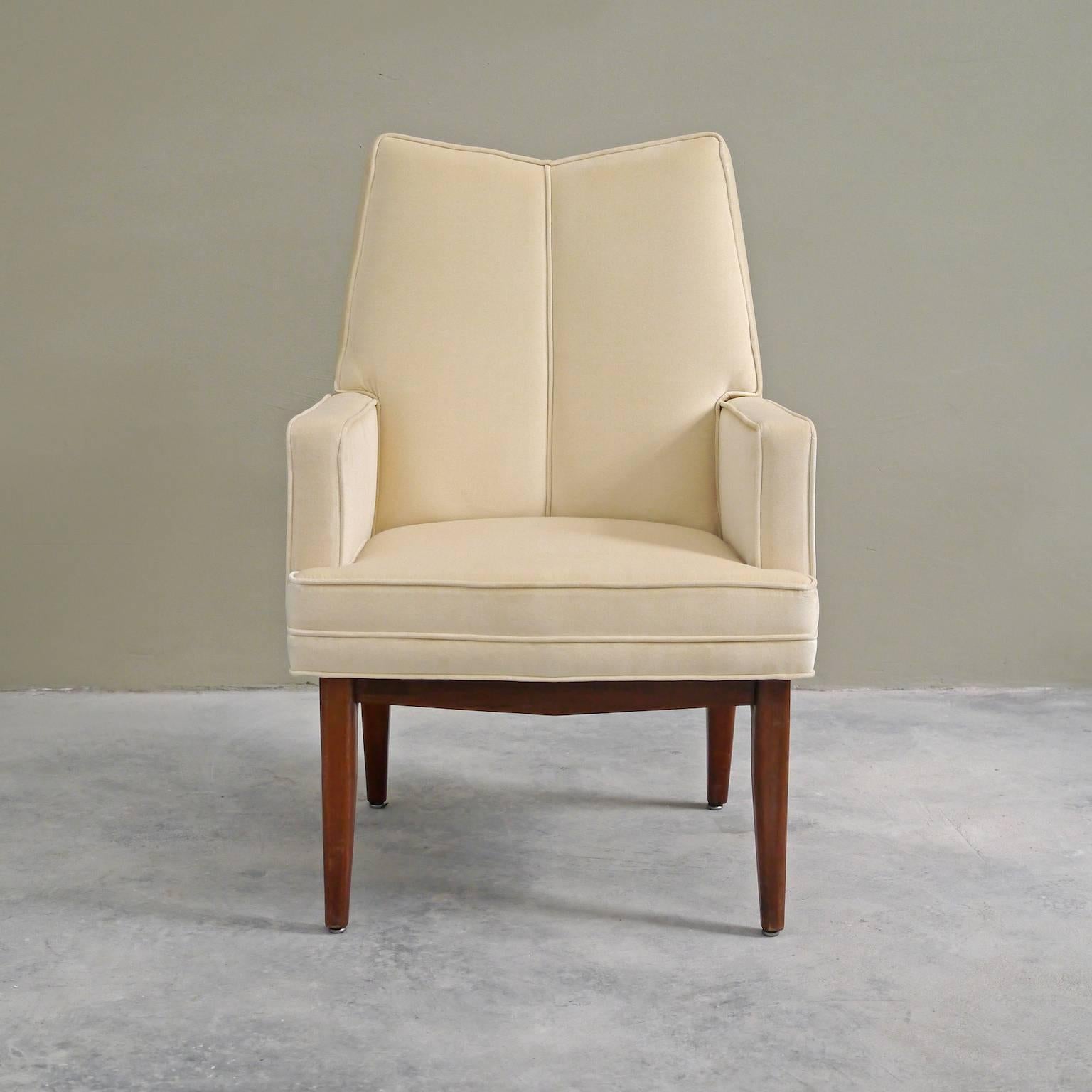 Sleek lines define this pair of newly produced chairs; from their V-form backs and vertical center seams, to their flared fruitwood legs. They are an homage to the influence of Mid-Century American design. Each chair is upholstered in creme colored