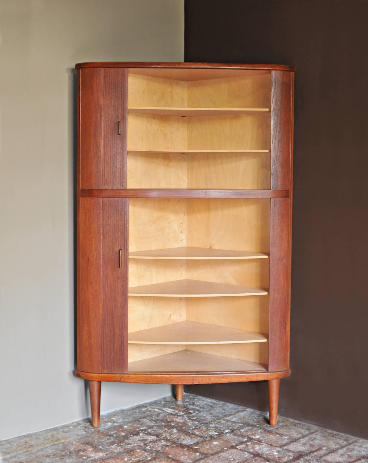 This is a beautiful Danish tambour door teak corner cabinet made by Skovmand and Andersen. The cabinet has three teak legs and two separate tambour doors with adjustable birch shelves.

Marked on back.