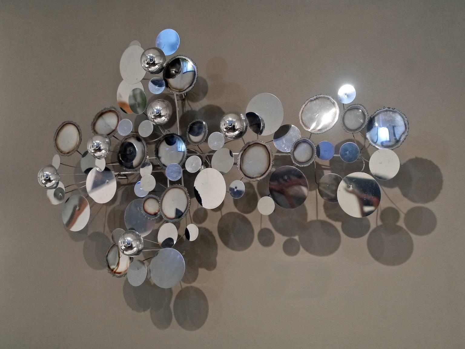 One of the most famed designs produced by Artisans House, the “raindrops” series was made of polished and burnished chromed metal disks and half globes. This piece has a signed and dated plate located on the back of the sculpture and may be hung