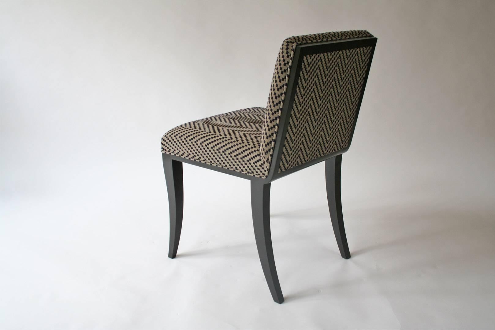 A black lacquer dining chair, created with a very low back allowing visual access to the dining table without the view being obstructed by a sea of upholstery fabric. The width and angle of the back make for a very comfortable seat with a smooth