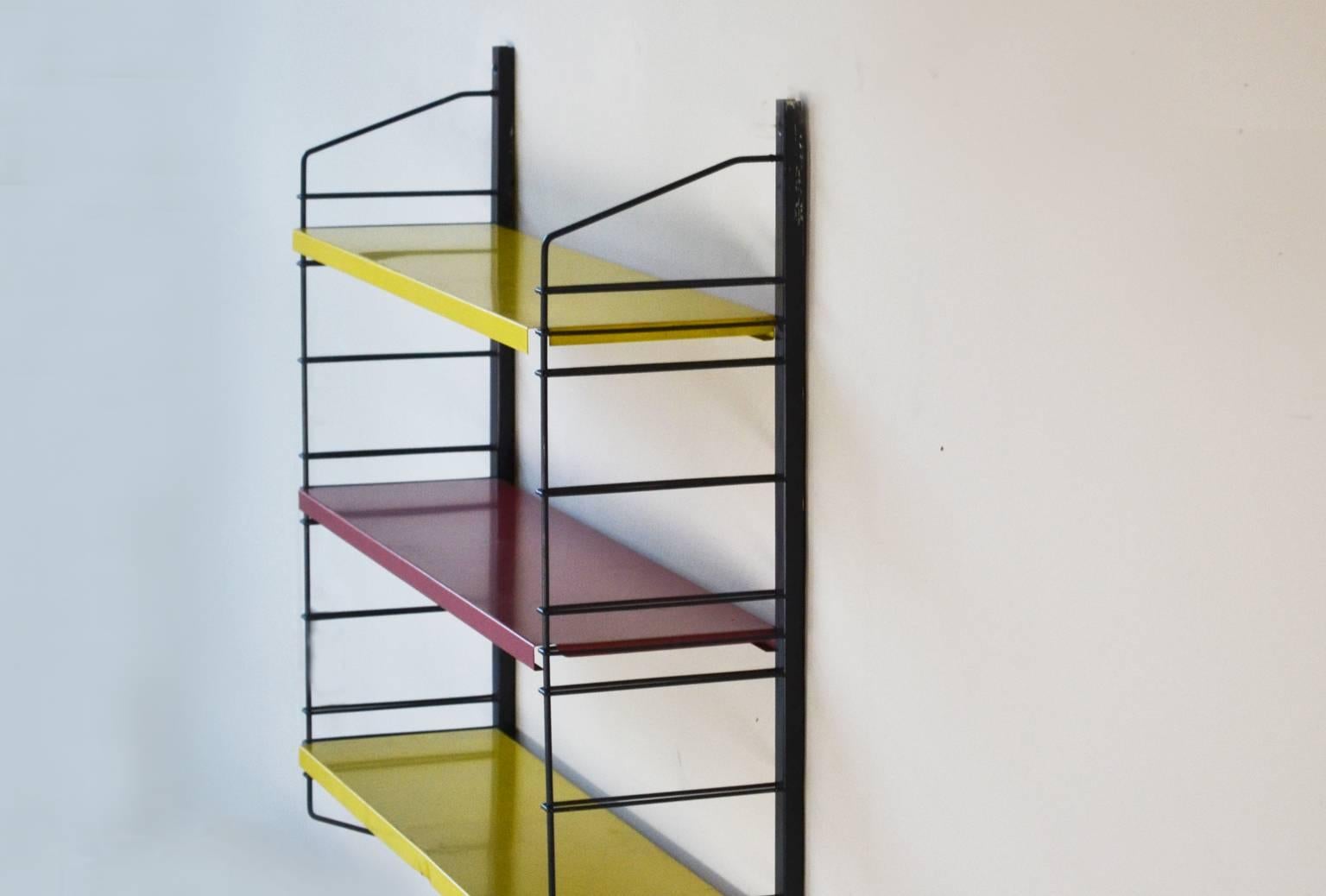 A modular, adjustable Tomado shelving system unit designed in the 1960s by Adriaan Dekker. The unit is in the original colors and finish, a black powder coated metal support frame with yellow and red painted shelves. The colors refer to the color