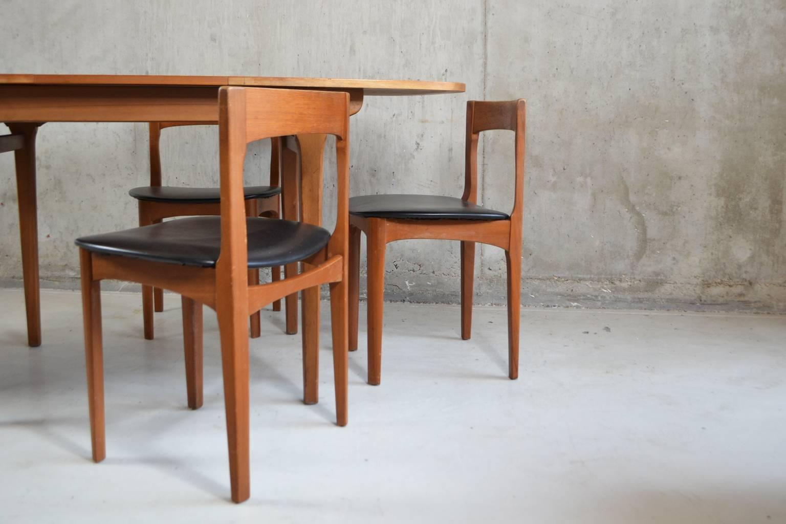 A stylish dining set by English furniture company Nathan. The table is an elegant shape with broad rounded corners. It extends by means of a tilting panel in the middle of the table. The matching chairs are teak with black vinyl seats.

Designer: