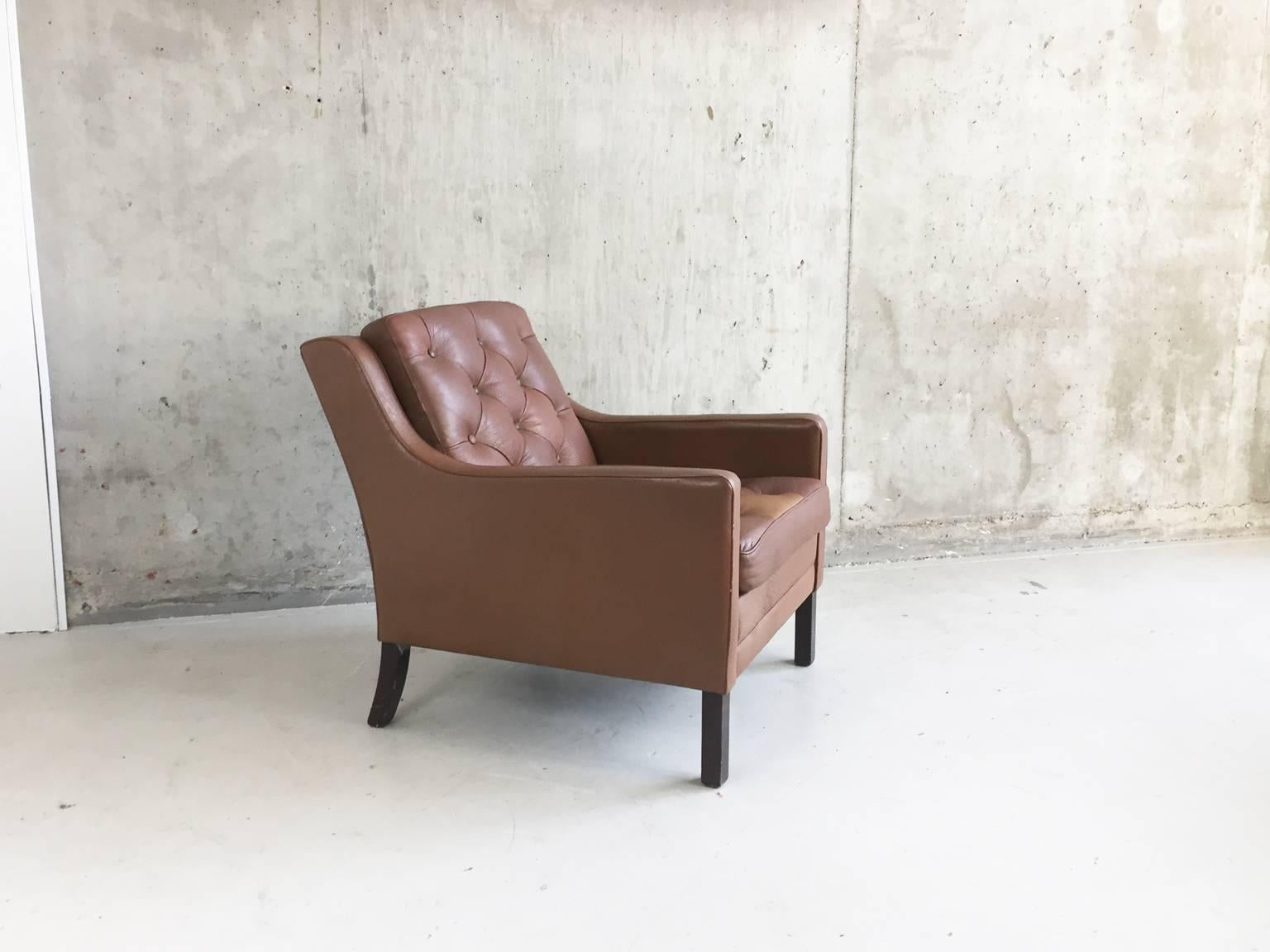 A very elegant original 1970s Danish club / lounge chair upholstered in the original leather with a wonderful buttoned and quilted effect on the back and seat cushion. One lighter brown segment in the middle of the front of the seat makes a very