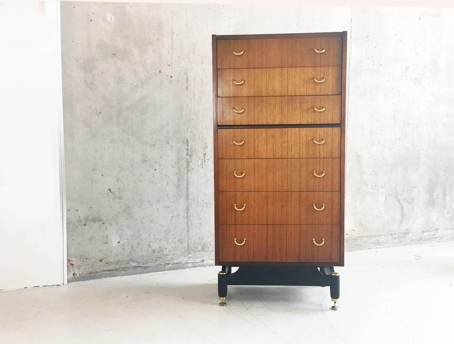 Mid-Century G Plan Tola chest of drawers tallboy in good sturdy condition. Standing on elegantly shaped ebonised legs with brass feet that are typical of the Tola range. this chest is in great vintage condition.
 