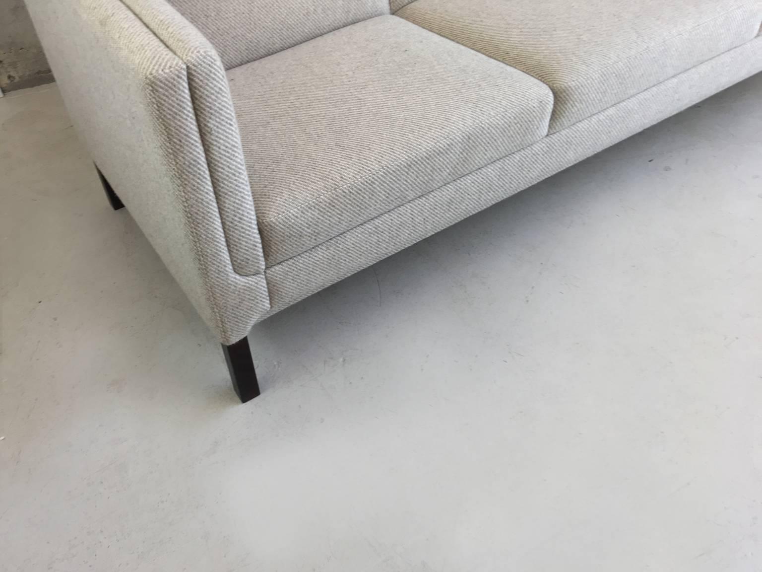 A minimal clean lined Danish three-seat sofa in incredible condition. The original fabric is light grey wool with a subtle herring bone pattern. It has double cushioned straight sides. The cushions are very firm. Extremely comfortable.
  