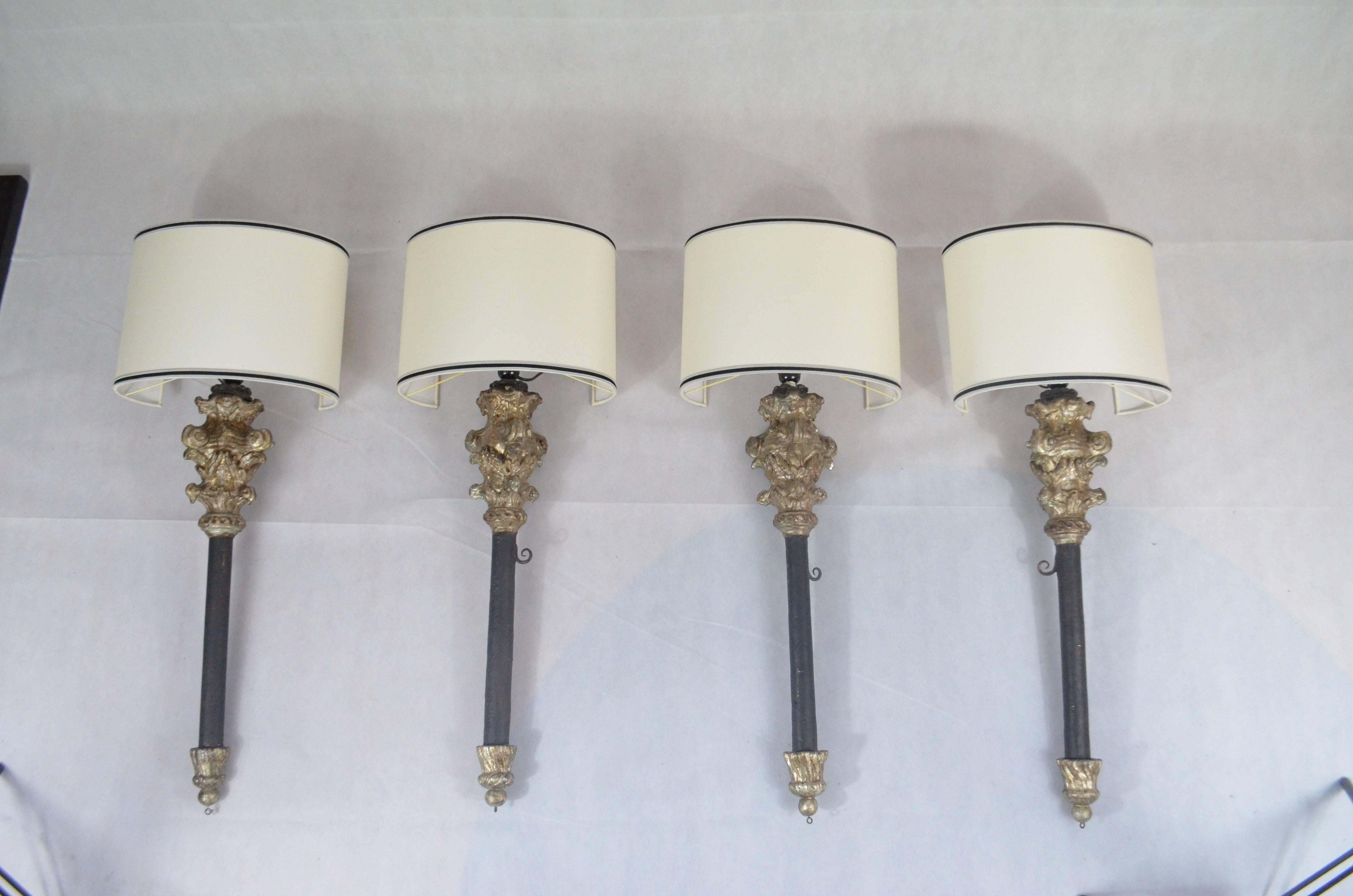 Two Louis XV, Italian torch holders finely engraved and decorated with silver leaf and mecca details. The central bar is ebonized. We fitted them for electricity, with new wirings and lamp holders. We have restored in a conservative way the wooden