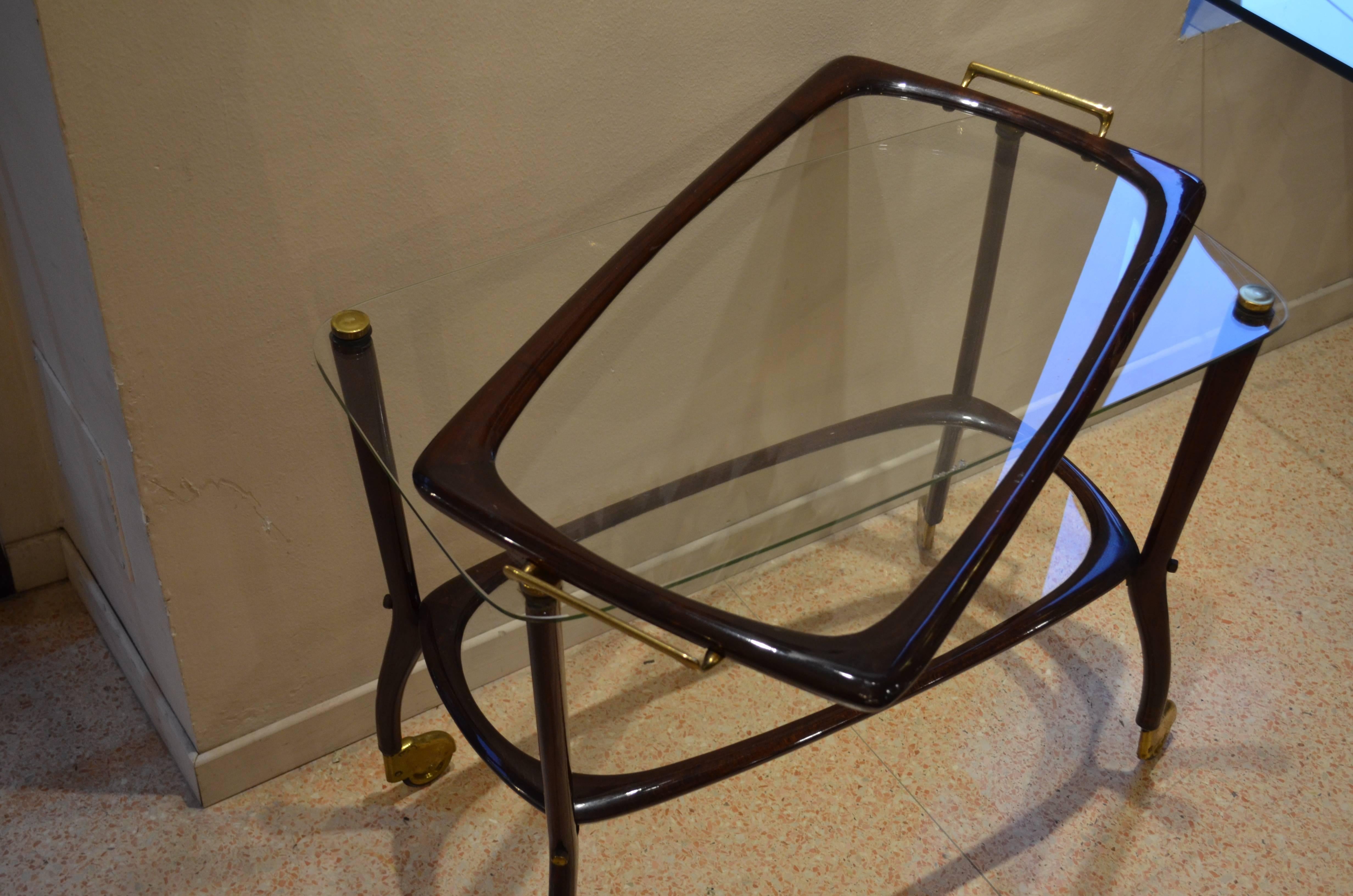 A wheels trolley made in rosewood with two crystal shelves. On the top of the highest one there is a removable tray. Four slots perfectly fit the four brass studs and keep the tray perfectly steady.
The tray is from Italy from 1960s. The wheels are