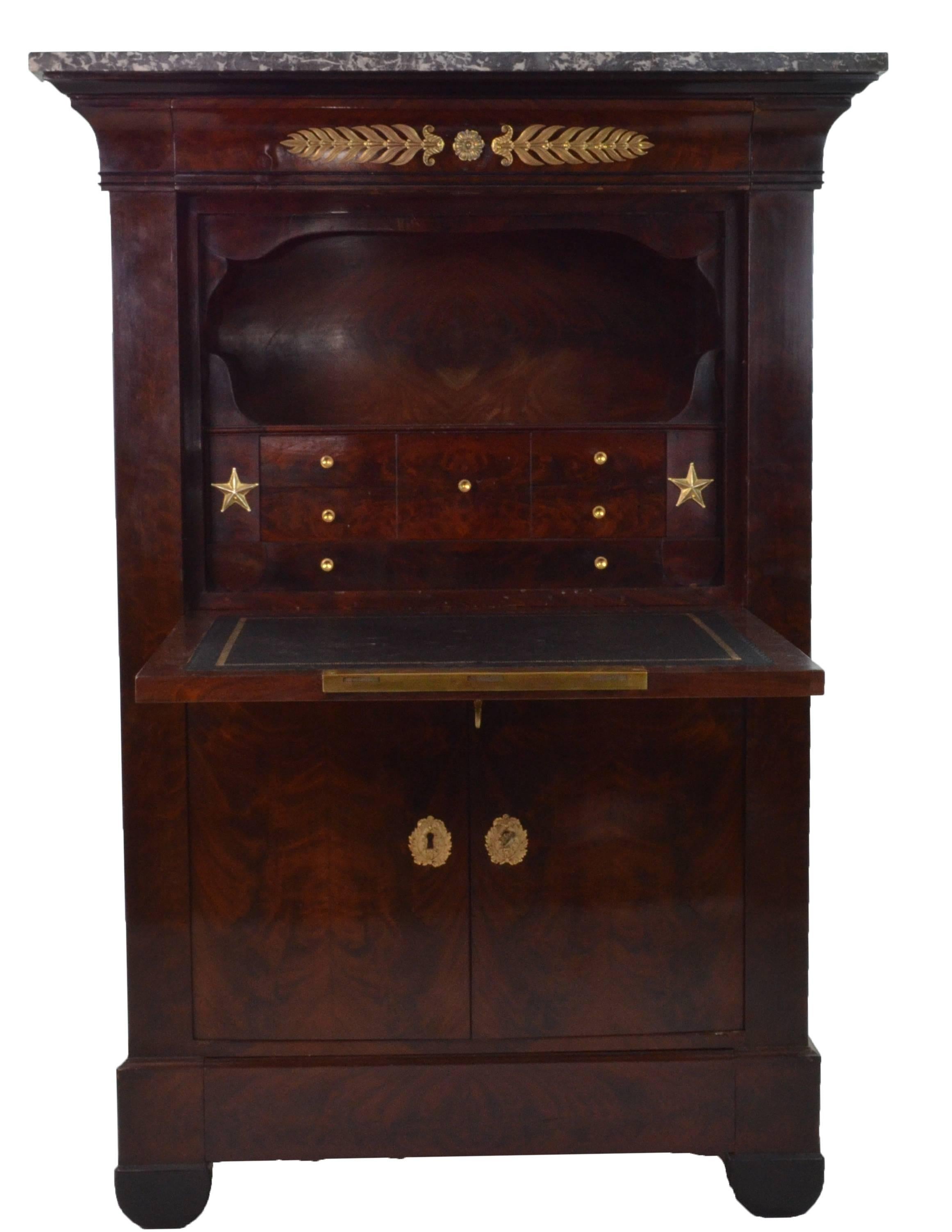 Empire Mahogany veneered folding desk secretaire. The folding desk is covered with recent black leather. There are some drawers both in the upper part, behind the folding door and in the lower part behind two doors. 
Hardware and locks are