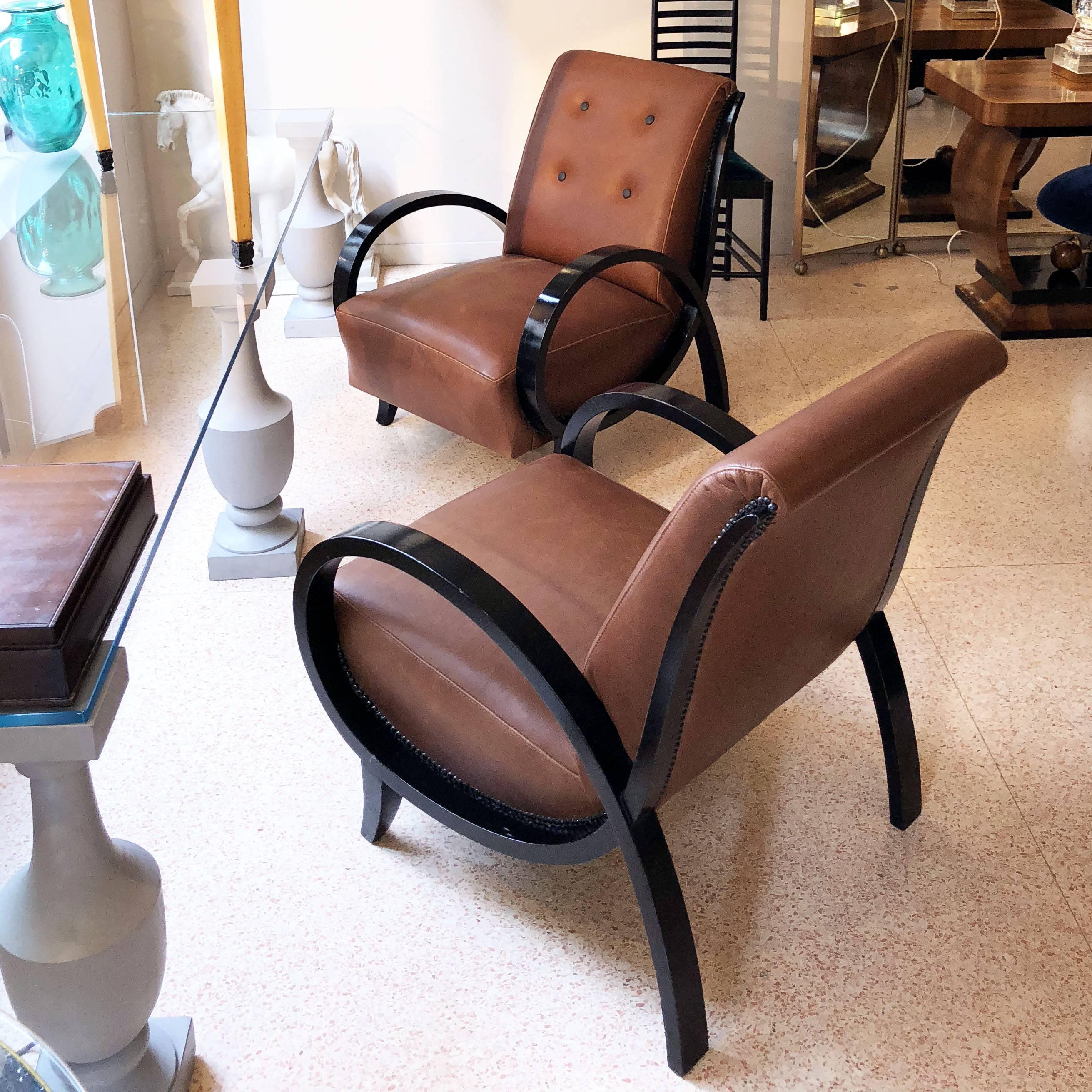 Armchairs from Art Deco period, circa 1930, black ebonized wood armrests and brown leather seats. The armchairs have been reupholstered with premium quality leather and wooden parts have been restored in a conservative way. Size: W 64 cm, D 70 cm, H