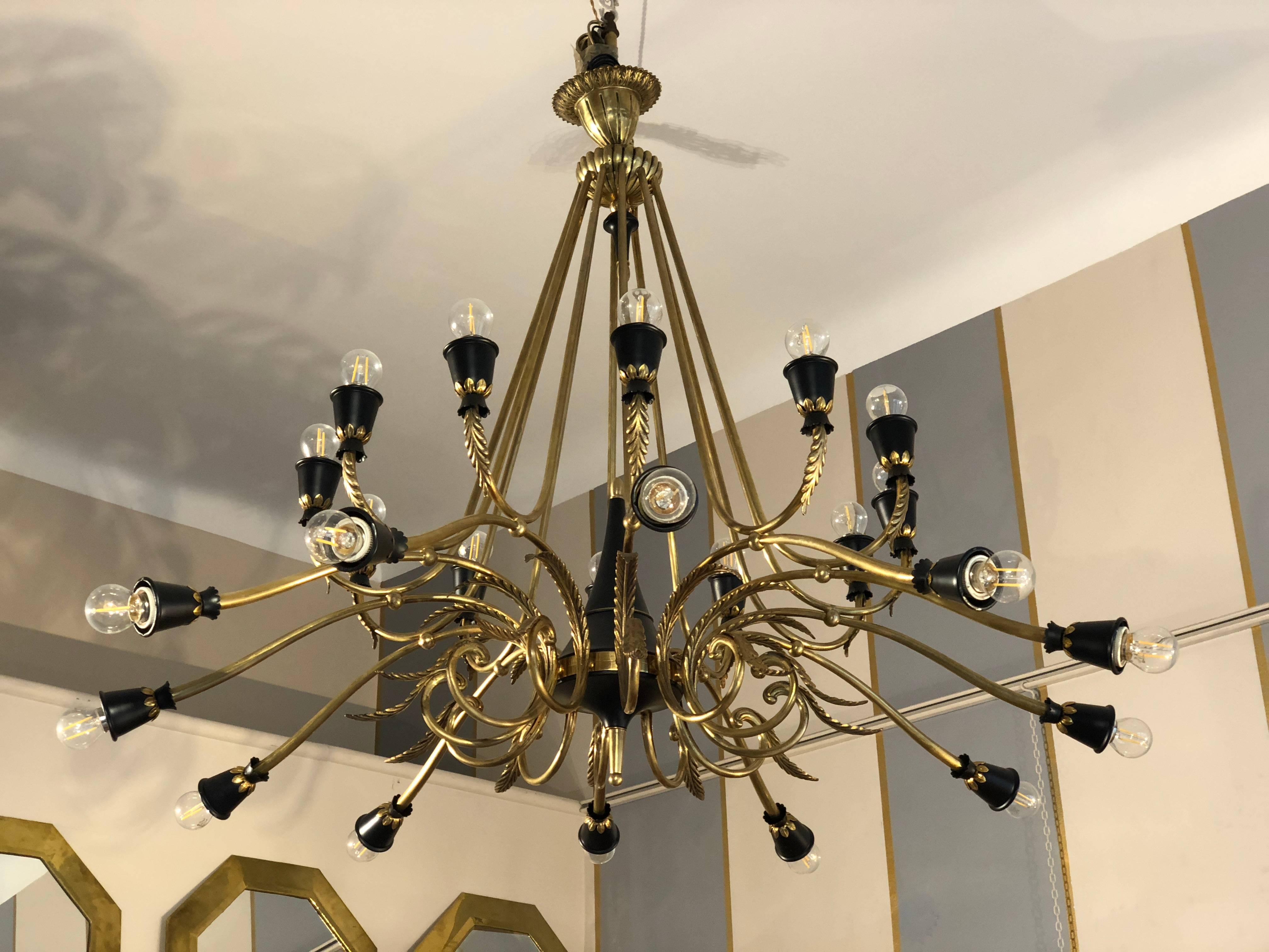 Brass chandelier, from Italy from 1950s period, 24 lights. It is composed by two separate lines of lights pointing upwards and downwards. There are 24 brass arms, one each bulb, each ending with a black light holder. This makes this chandelier