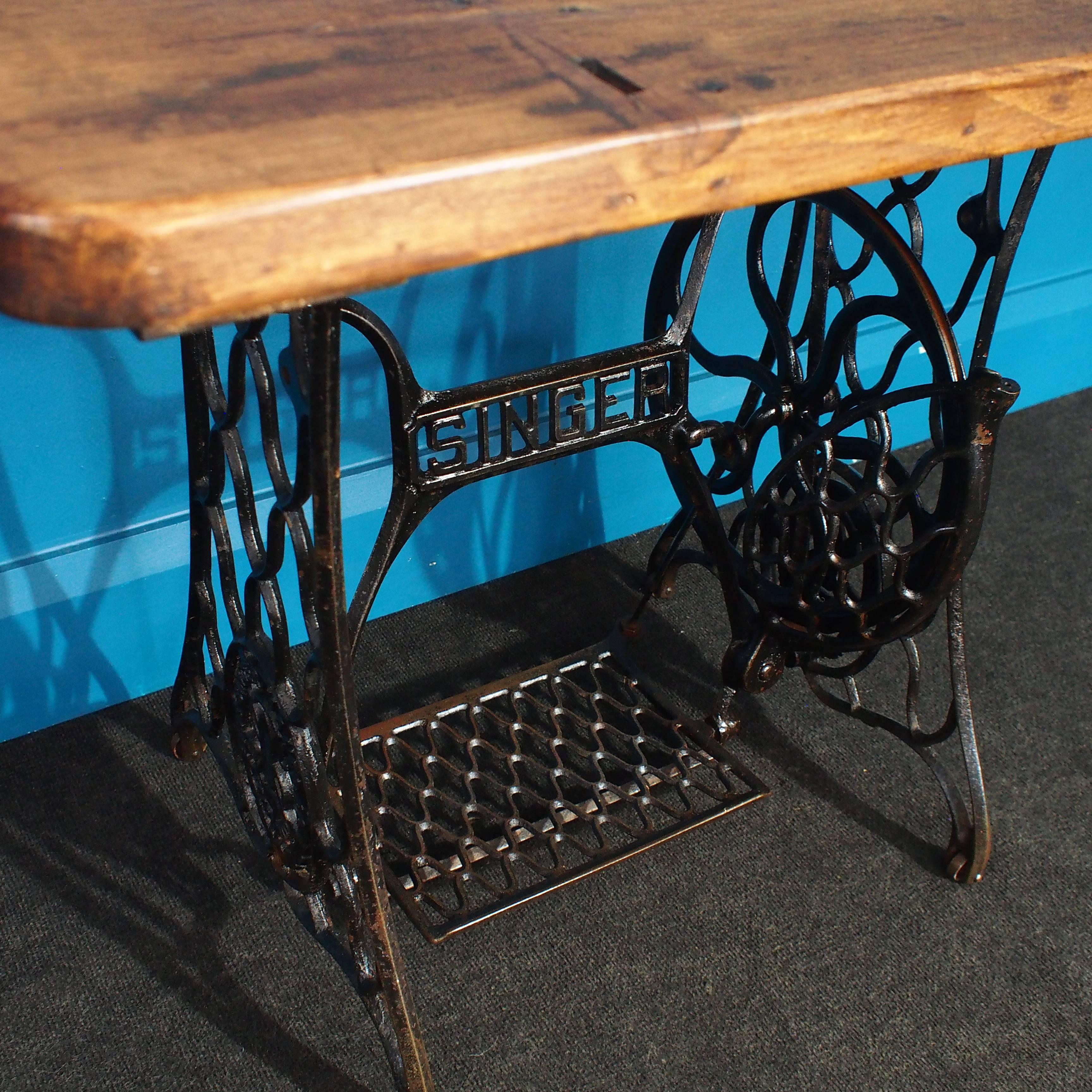 Complete with its original integral casters, foot plate and drive wheel and with the addition of a deep reclaimed timber plank top, this vintage cast iron Singer sewing machine base has been professionally transformed into an authentic vintage