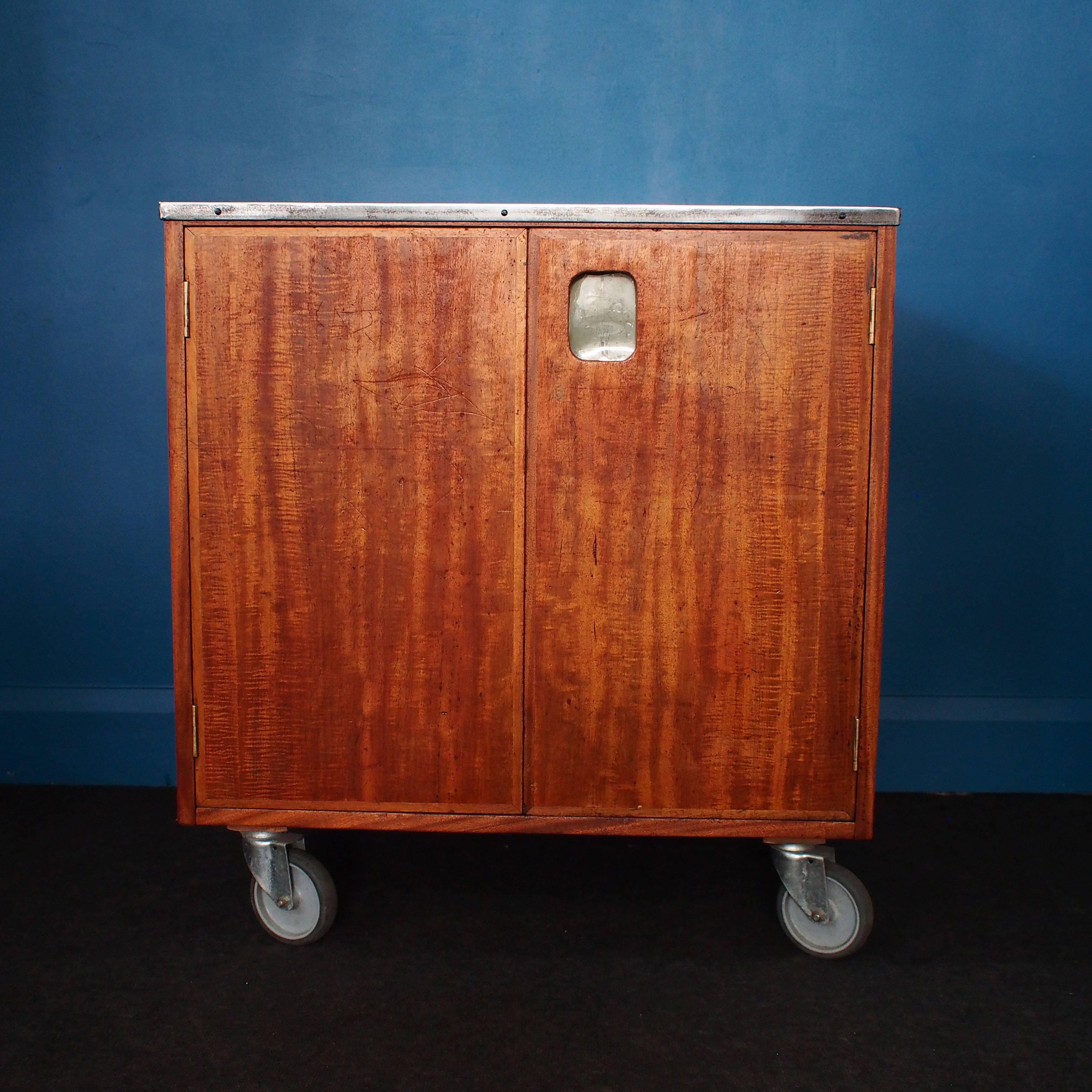 By Wrinch & Sons and dating back to 1955, this vintage Art School Unit is set on lockable casters and has nine dovetail-jointed drawers on one side and a Shelved cupboard with twin doors on the other side. Topped with a polished steel Worktop this