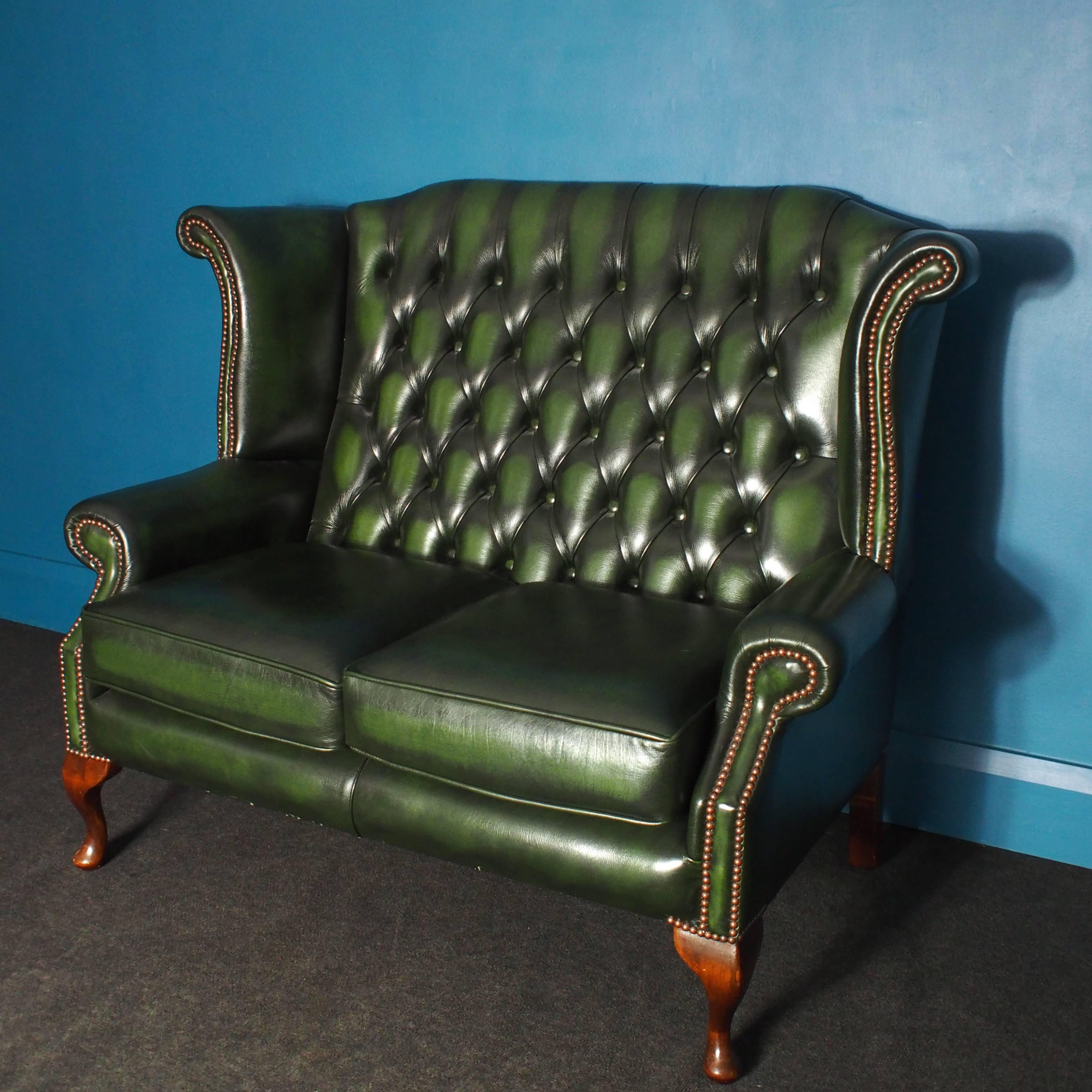 In fabulous 'hardly-sat-on' condition, this handsome two-seat wingback Chesterfield sofa has cabriole legs at the front and angular legs at the rear. The two-seat cushions are removable. Other than minor surface scuffs on the legs, this sofa remains