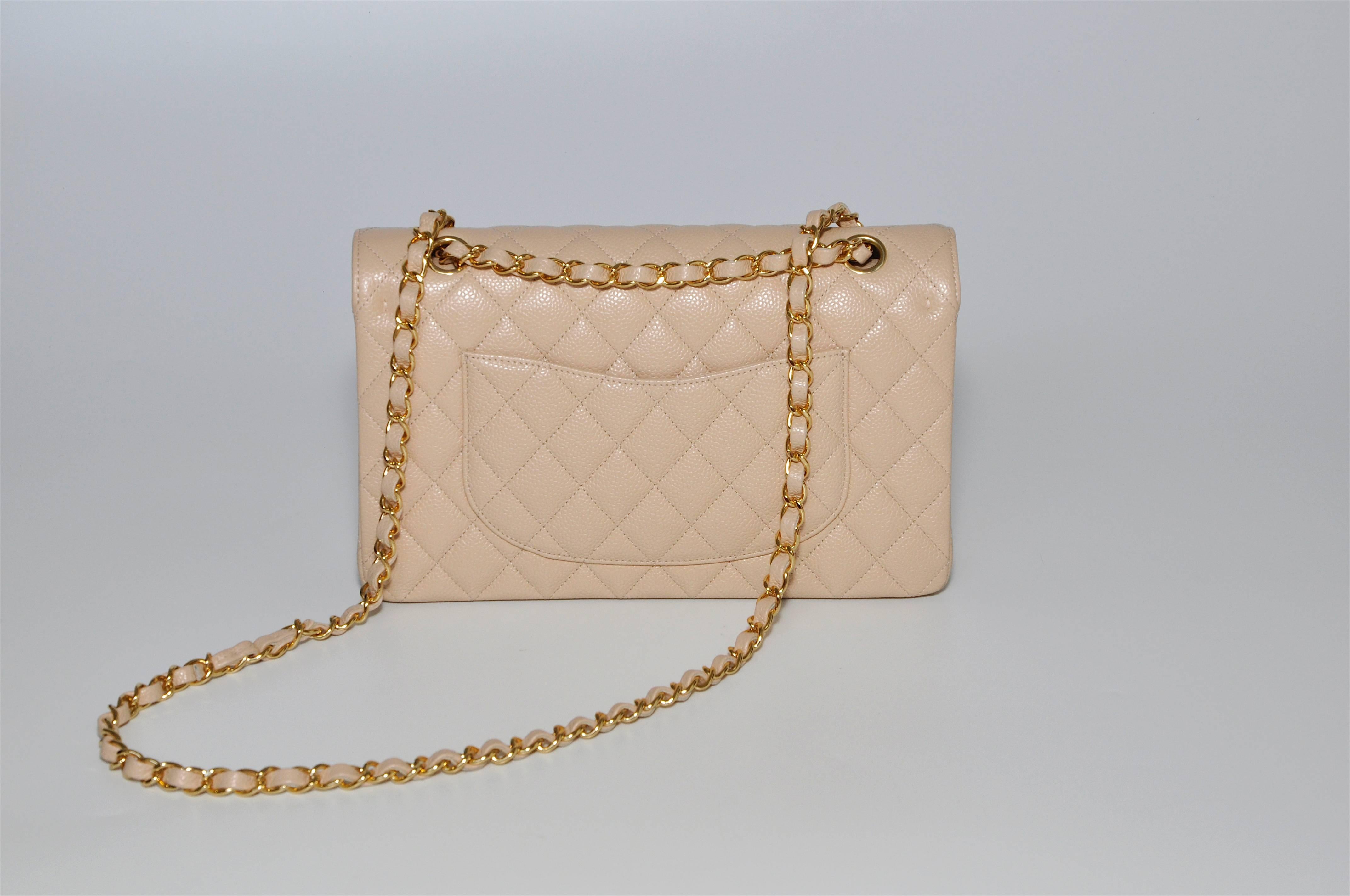 Classic Chanel bag in a beautiful beige creamy coloured quilted calfskin leather in caviar (subtle textured grainy finish) with gold metal hardware. This is an iconic design that has been synonymous with the fashion house for years, as of 2016 it is